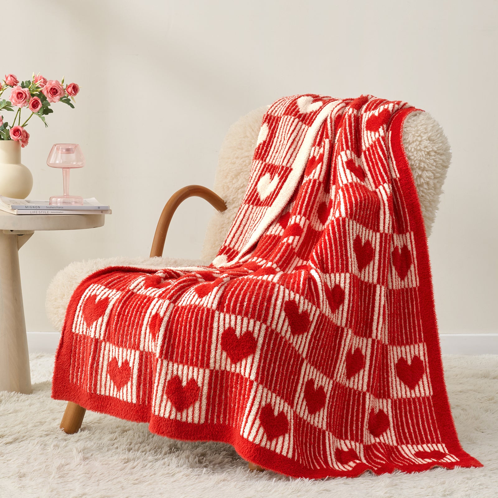 Red and white patterned blanket draped over a chair in a cozy room. #color_Red Heart