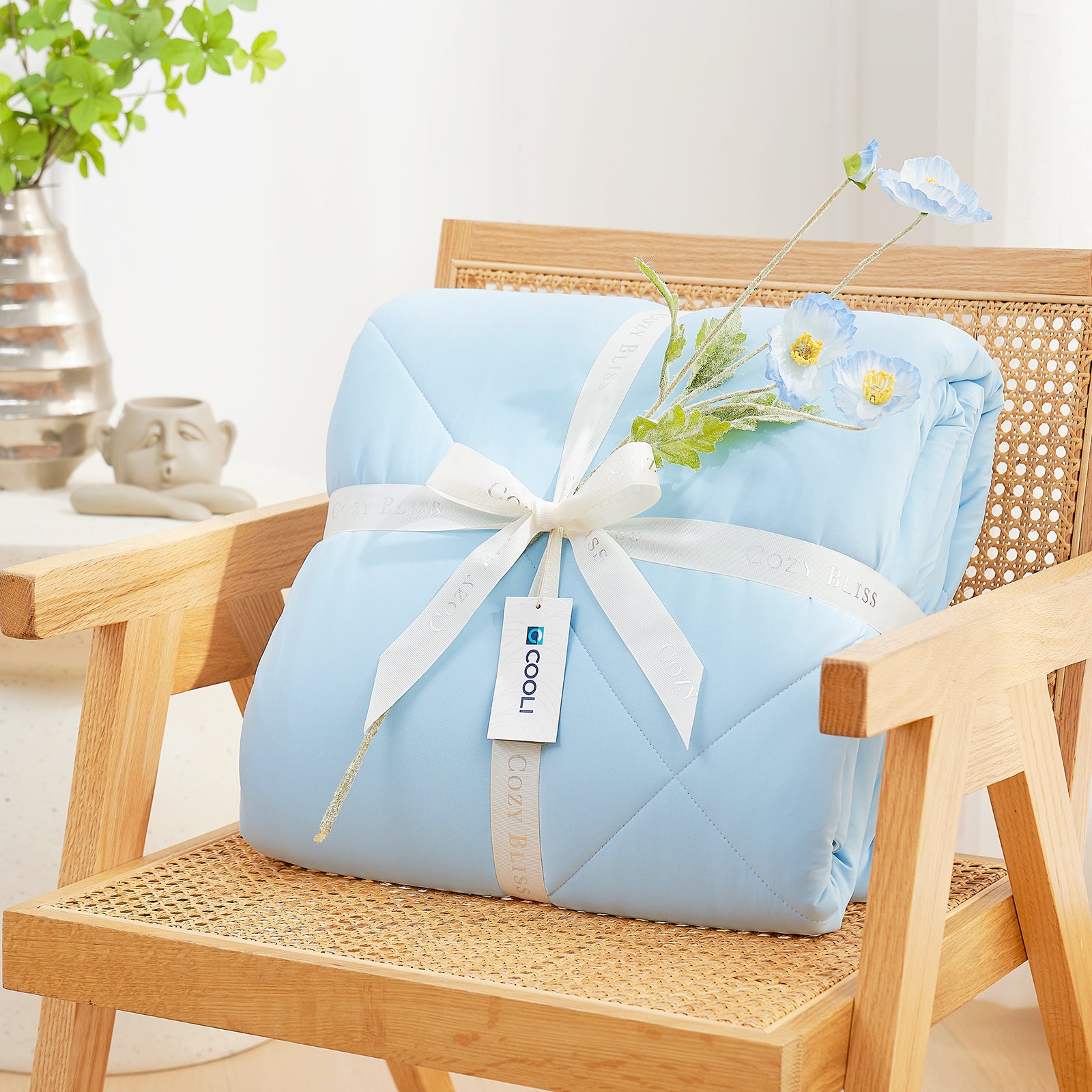 Cooling comforter with a white ribbon on a wooden chair, perfect as gift.#color_Sky Blue
