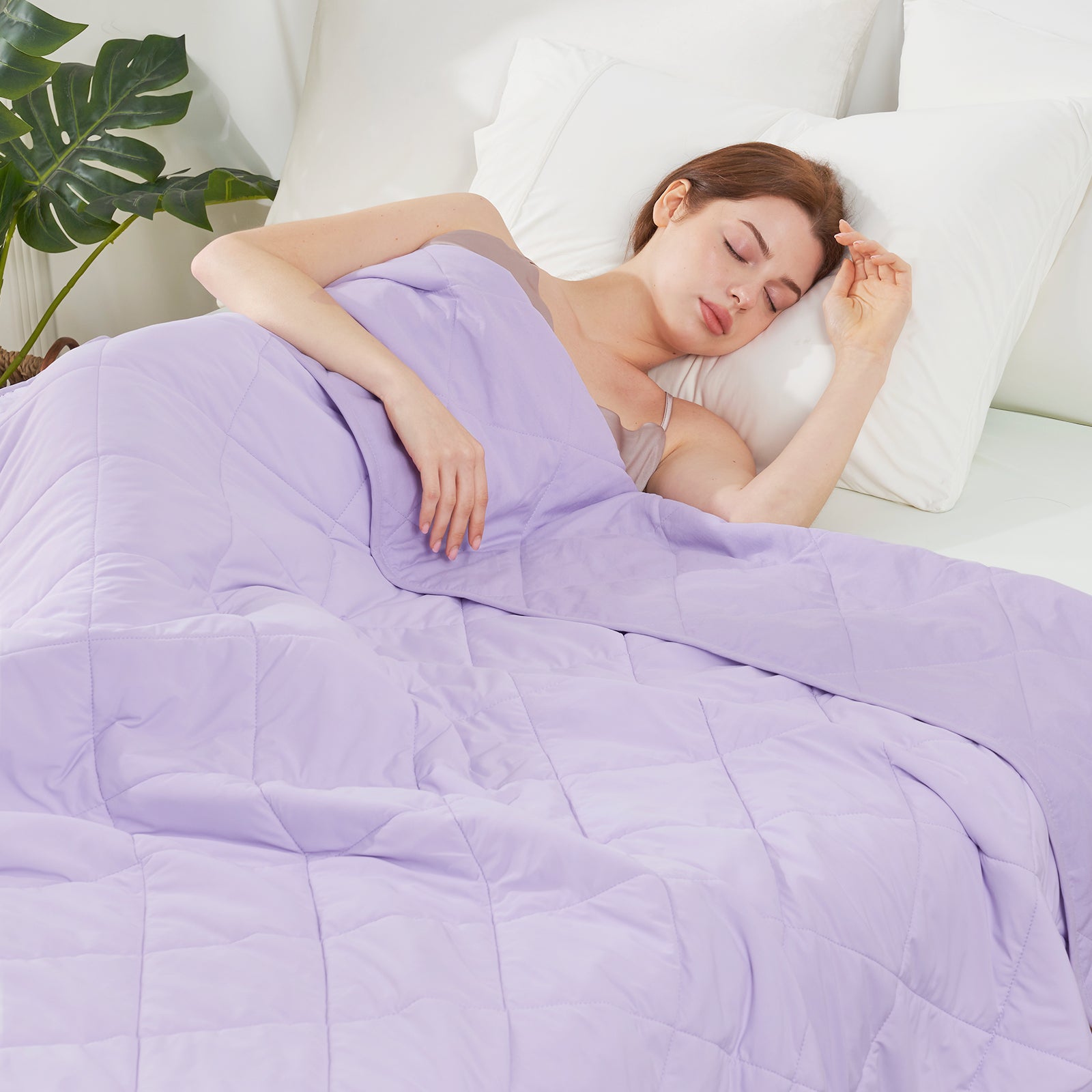 Woman sleeping under a purple comforter in a bedroom setting#color_Purple