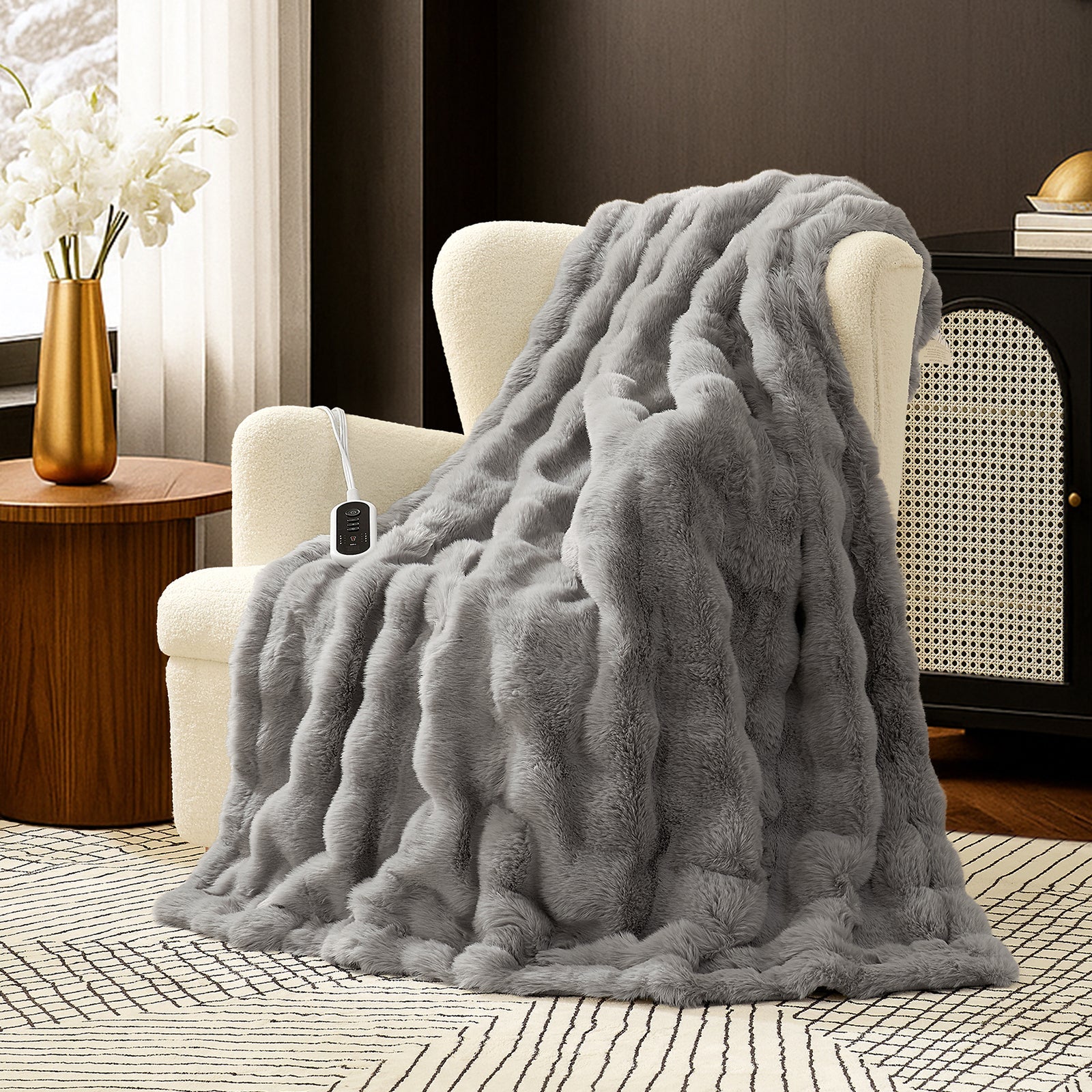 Woman sitting on a couch with a gray fuzzy blanket wrapped around her, using a laptop. #color_Light Grey