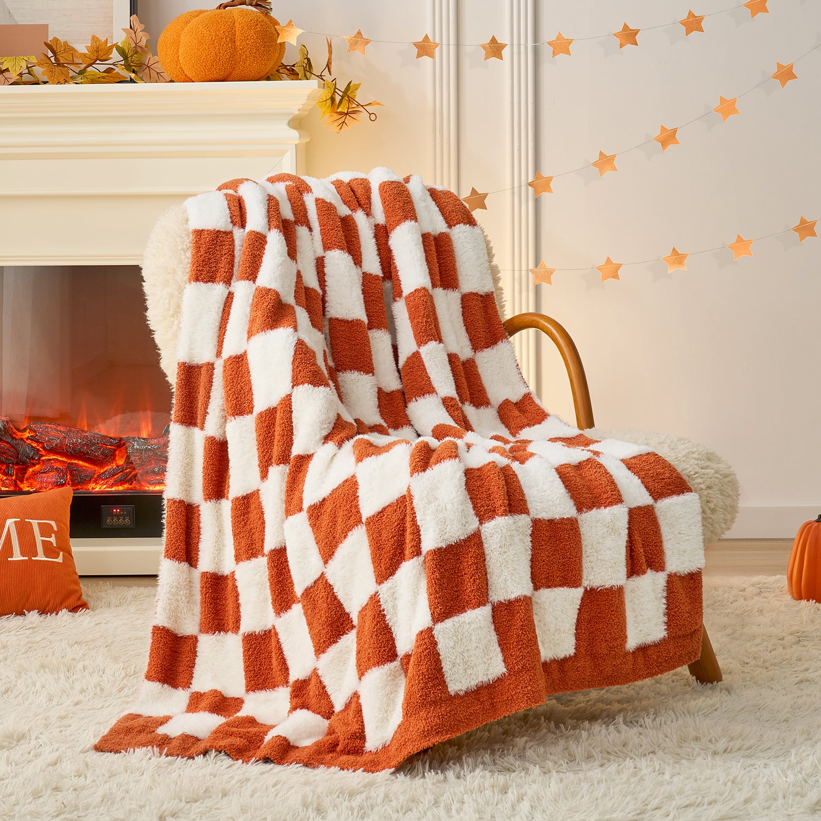 Checkered orange and white blanket draped over a chair in a cozy room with a fireplace and pumpkins. #color_Orange