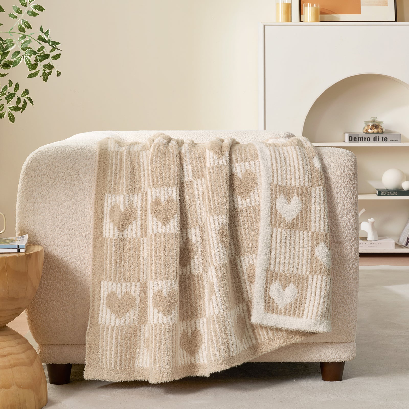 Beige blanket with heart patterns draped over a chair in a cozy living room. #color_Cream/Beige