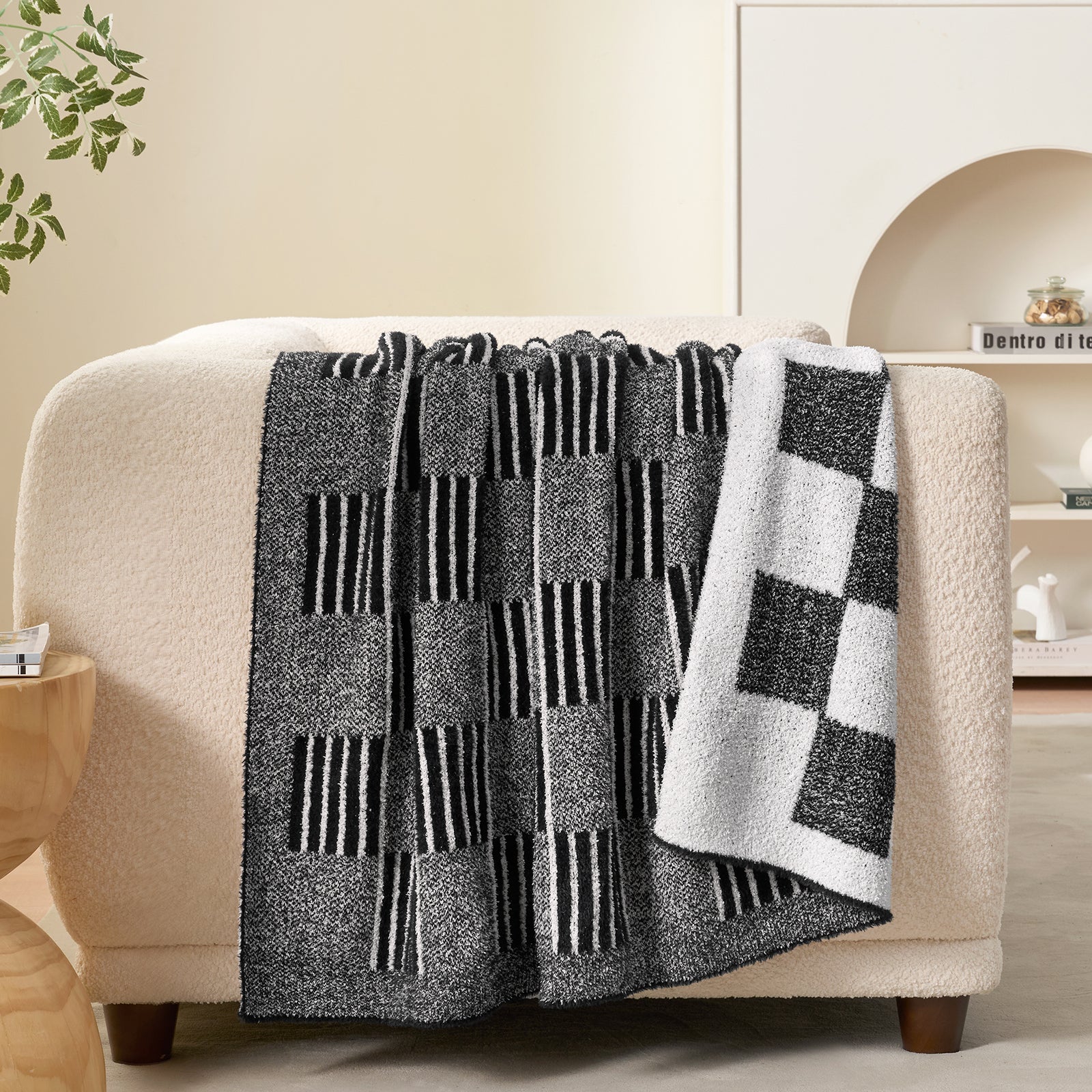 Black and white patterned throw blanket draped over a beige armchair in a living room setting. #color_Heather Black