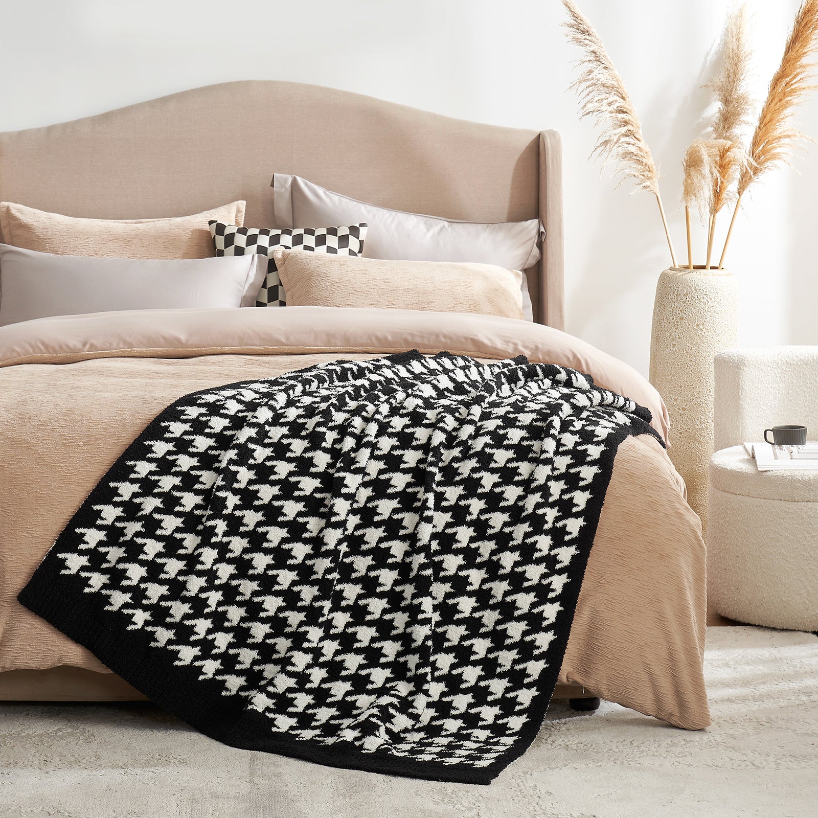 Bed with beige bedding, black and white patterned throw blanket, and decorative pillows in a cozy bedroom setting. #color_Black