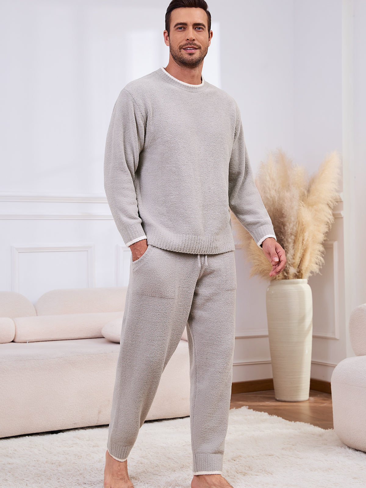 Man wearing a gray sweater and pants in a living room setting. #color_Light Grey