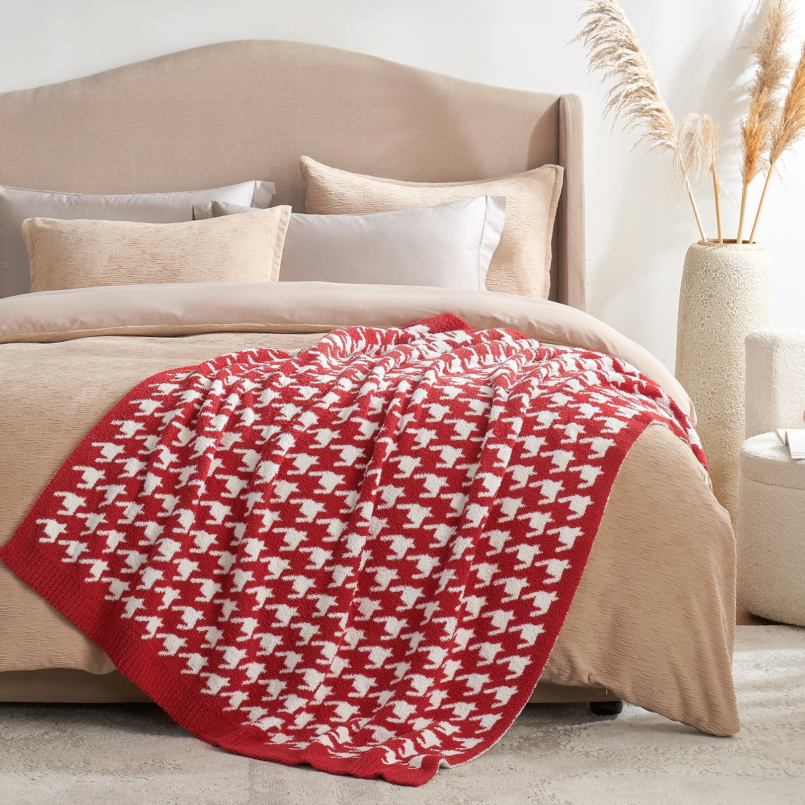 Red and white patterned blanket on a bed with beige bedding and pillows. #Color_Red/Cream