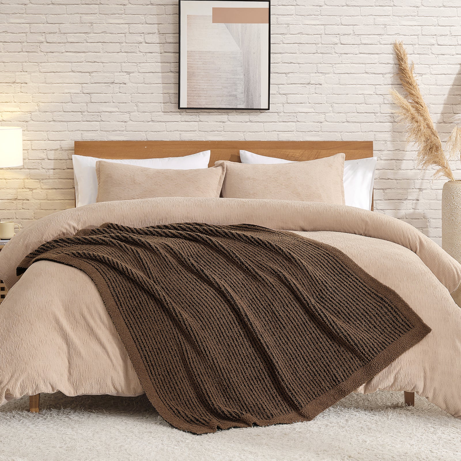 Beige bedding set with a brown throw blanket on a bed against a white brick wall. #color_Brown/Black