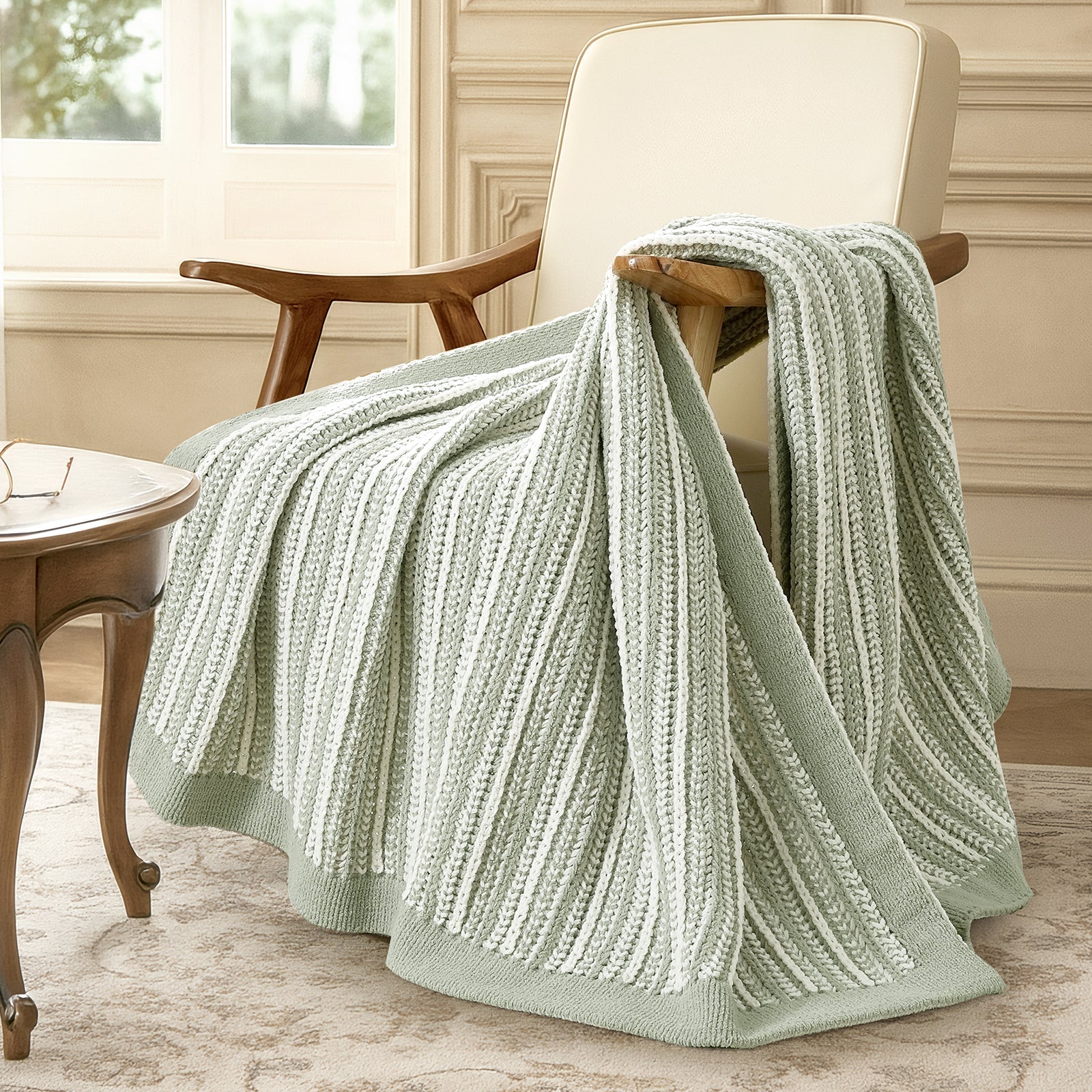 Green knitted blanket draped over a chair in a cozy room. #color_Sage Green