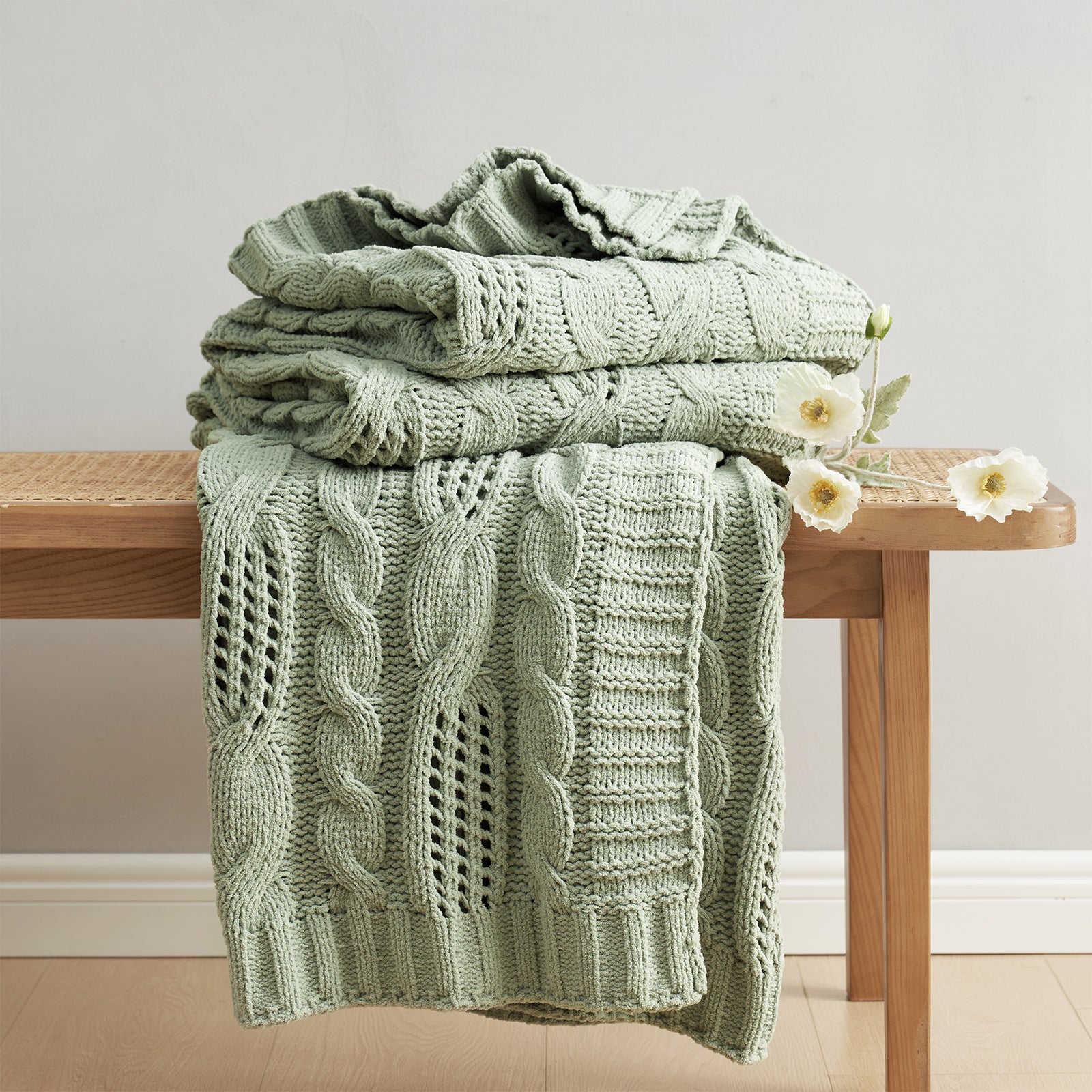 Cable chenille knit throw blanket in Sage Green neatly folded on a wooden table showcasing cable texture #color_Sage Green