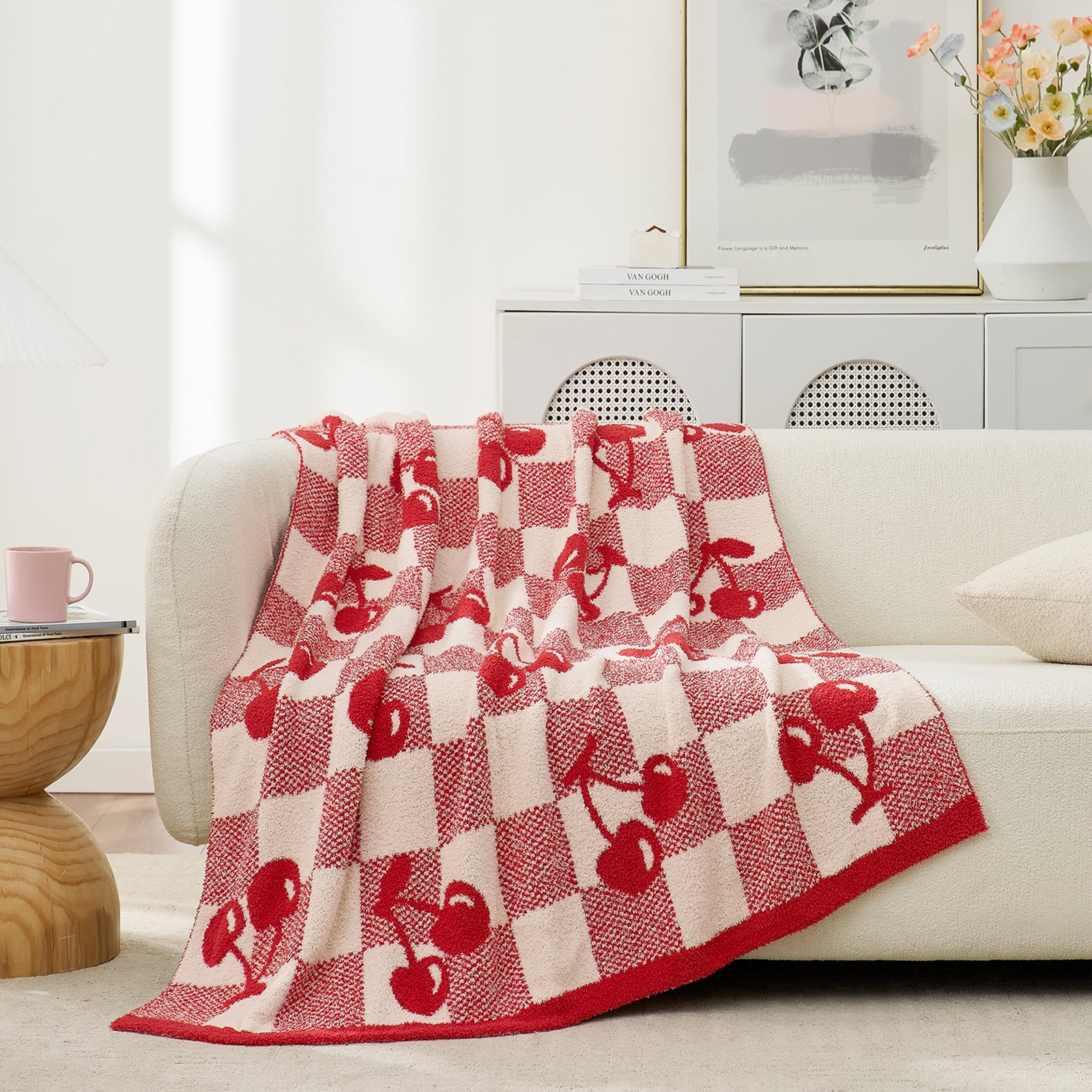 Snuggle Sacs Red Cherry Feather Yarn Knit Throw Blanket drapped on the beige couch with a vase of flower behind#color_Red_Cherry