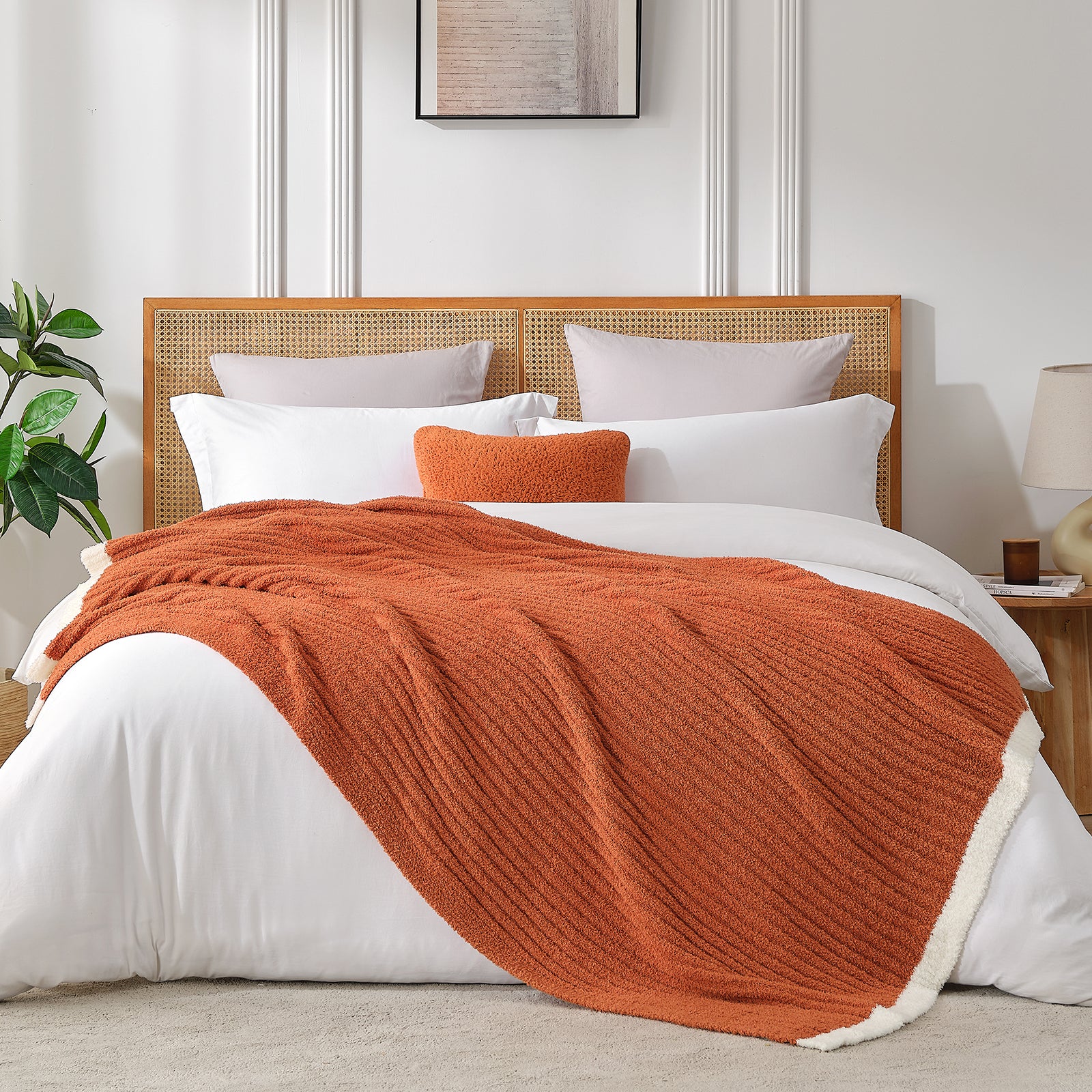 Bed with orange throw blanket and white pillows in a bedroom setting #color_Burnt Orange