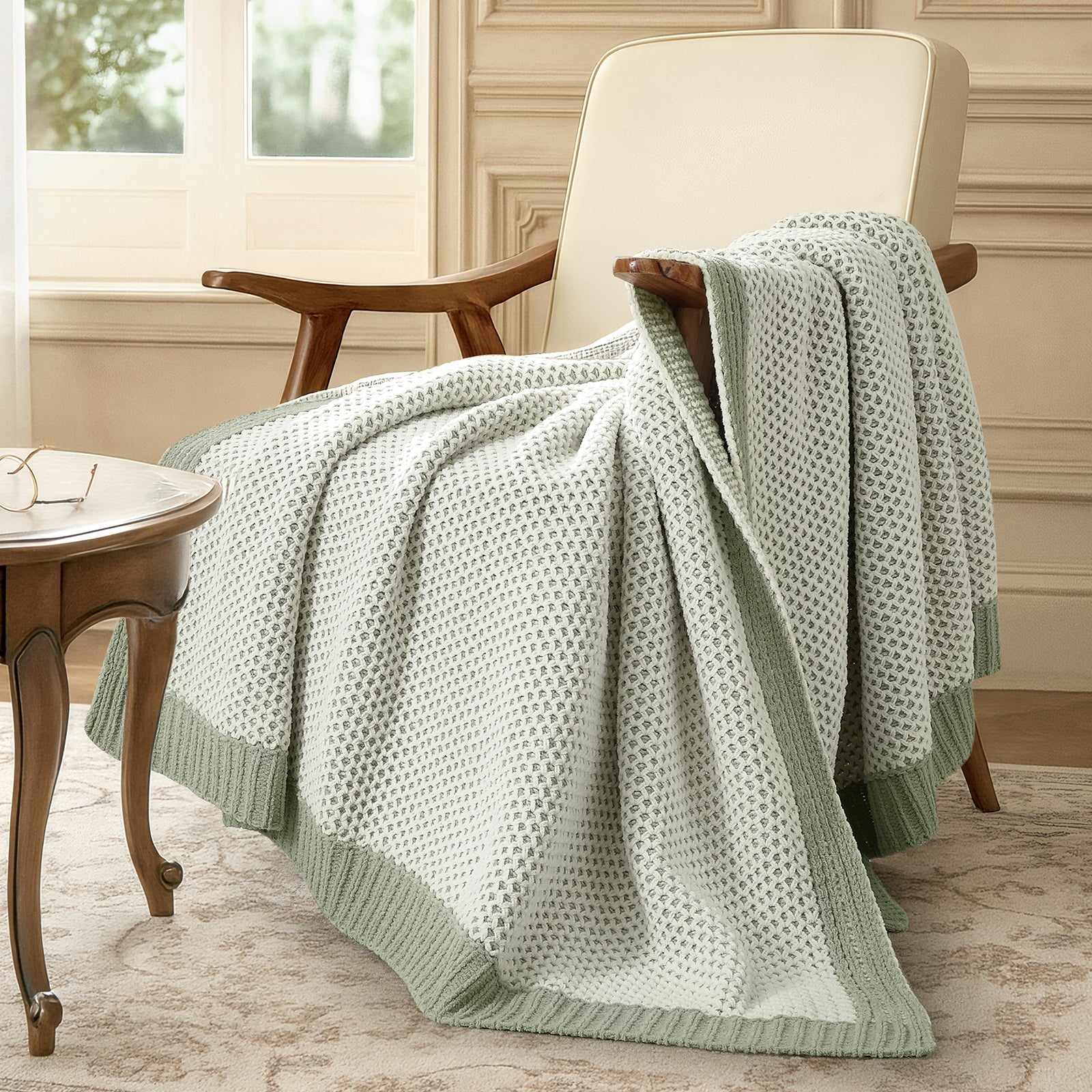 Snuggle Sac light green textured blanket draped over a chair in a room with a window and table. #color_Sage Green