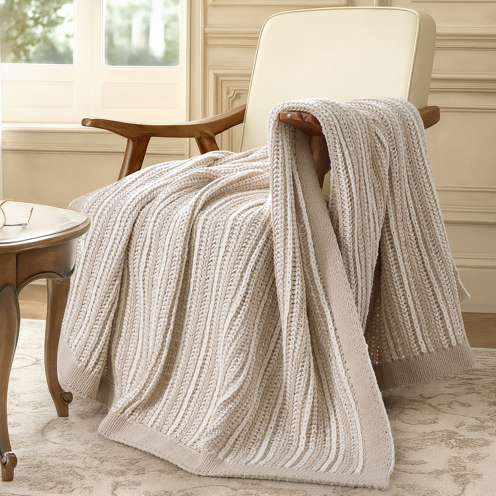 Snuggle Sac knitted blanket draped over a chair in a cozy room. #color_Khaki&White