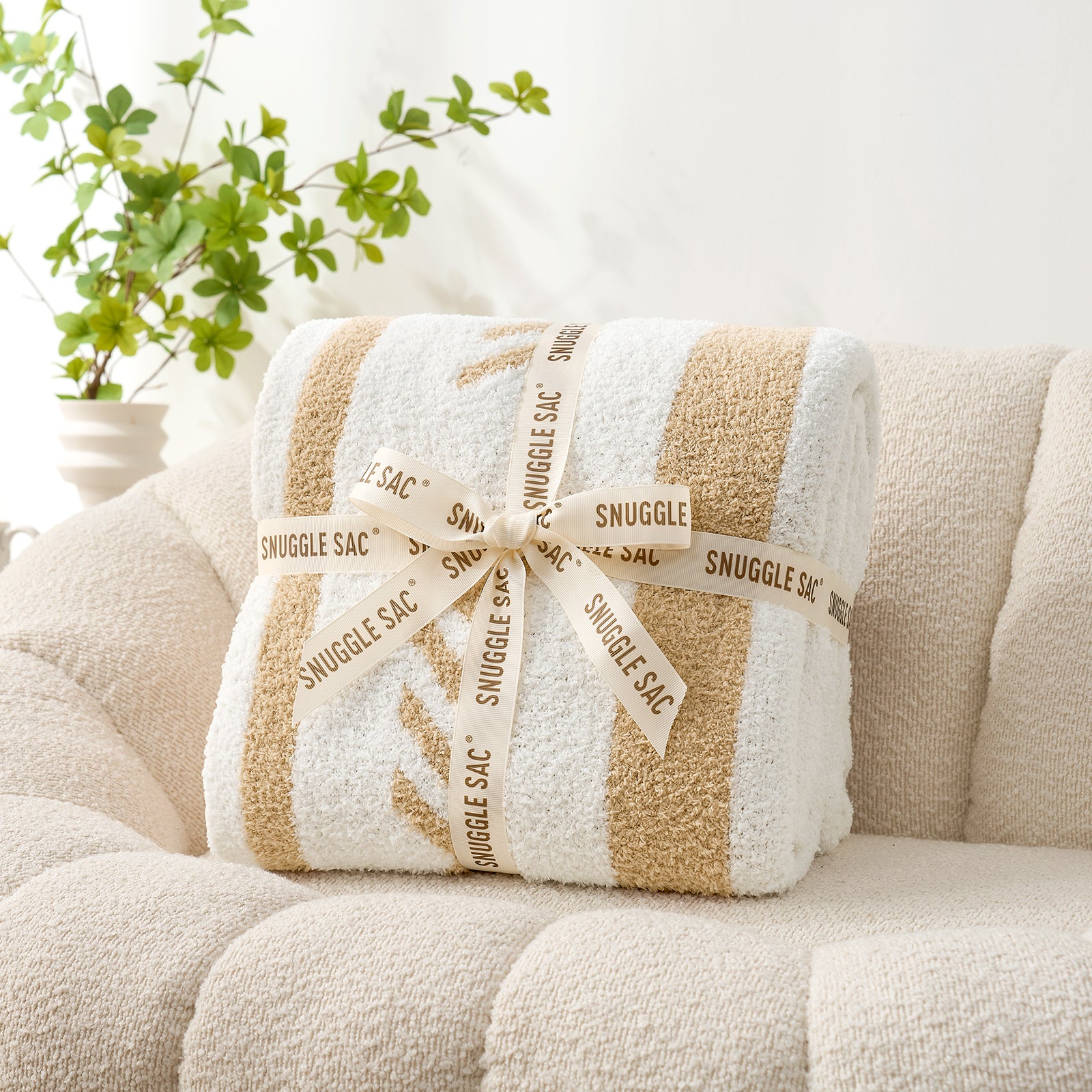 Snuggle Sacs Reversible Boho Feather Yarn Knit Throw Blanket wrapped in a ribbon as a perfect gift#color_beige