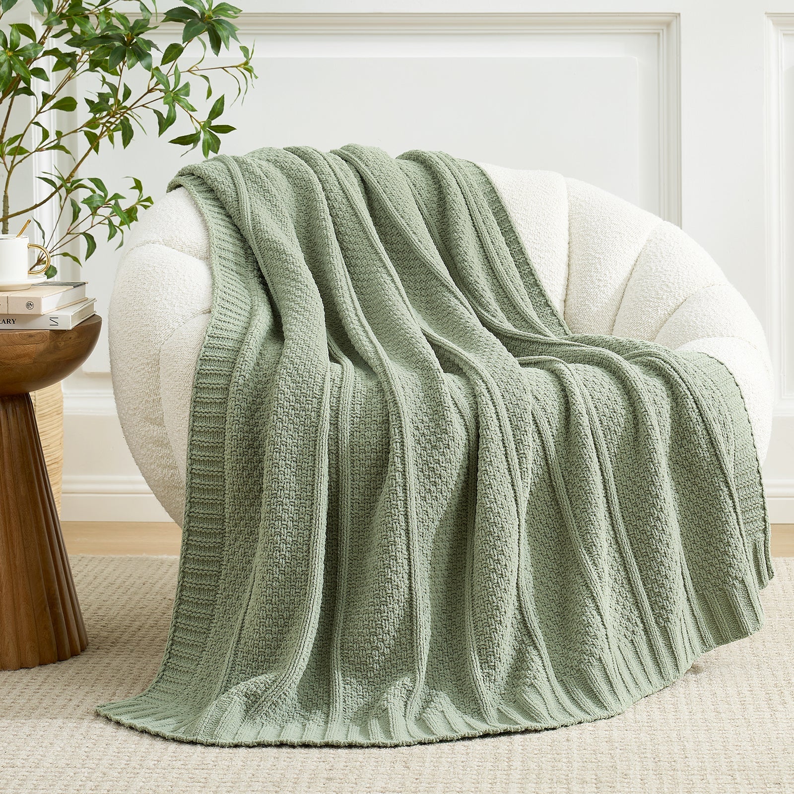 Green knitted blanket draped over a white chair in a cozy living room setting. #color_Sage Green