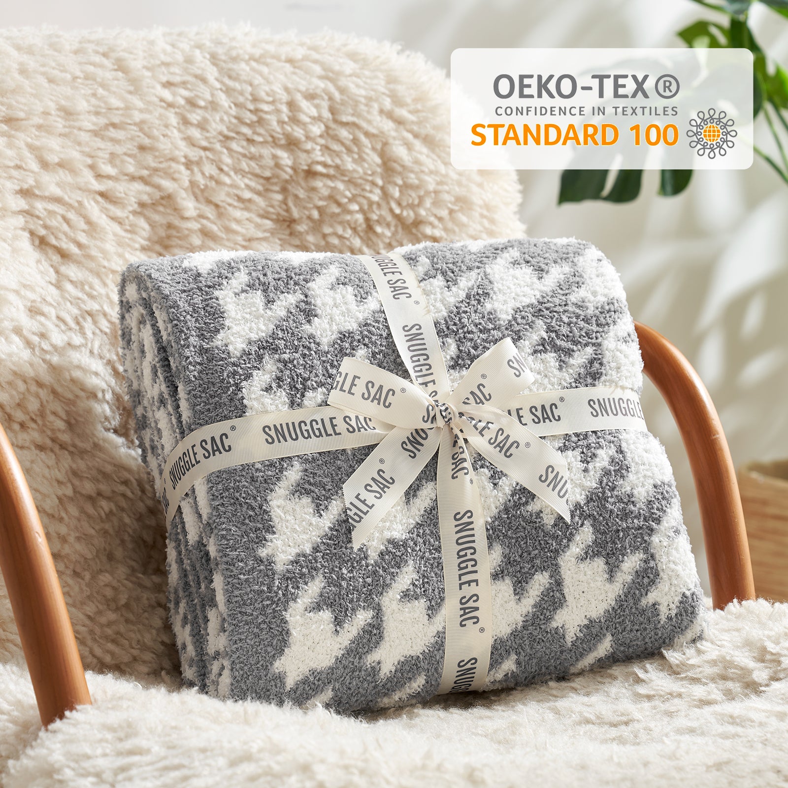 Folded blanket with 'Snuggle Sac' branding on a soft surface, featuring OEKO-TEX certification. #color_Grey