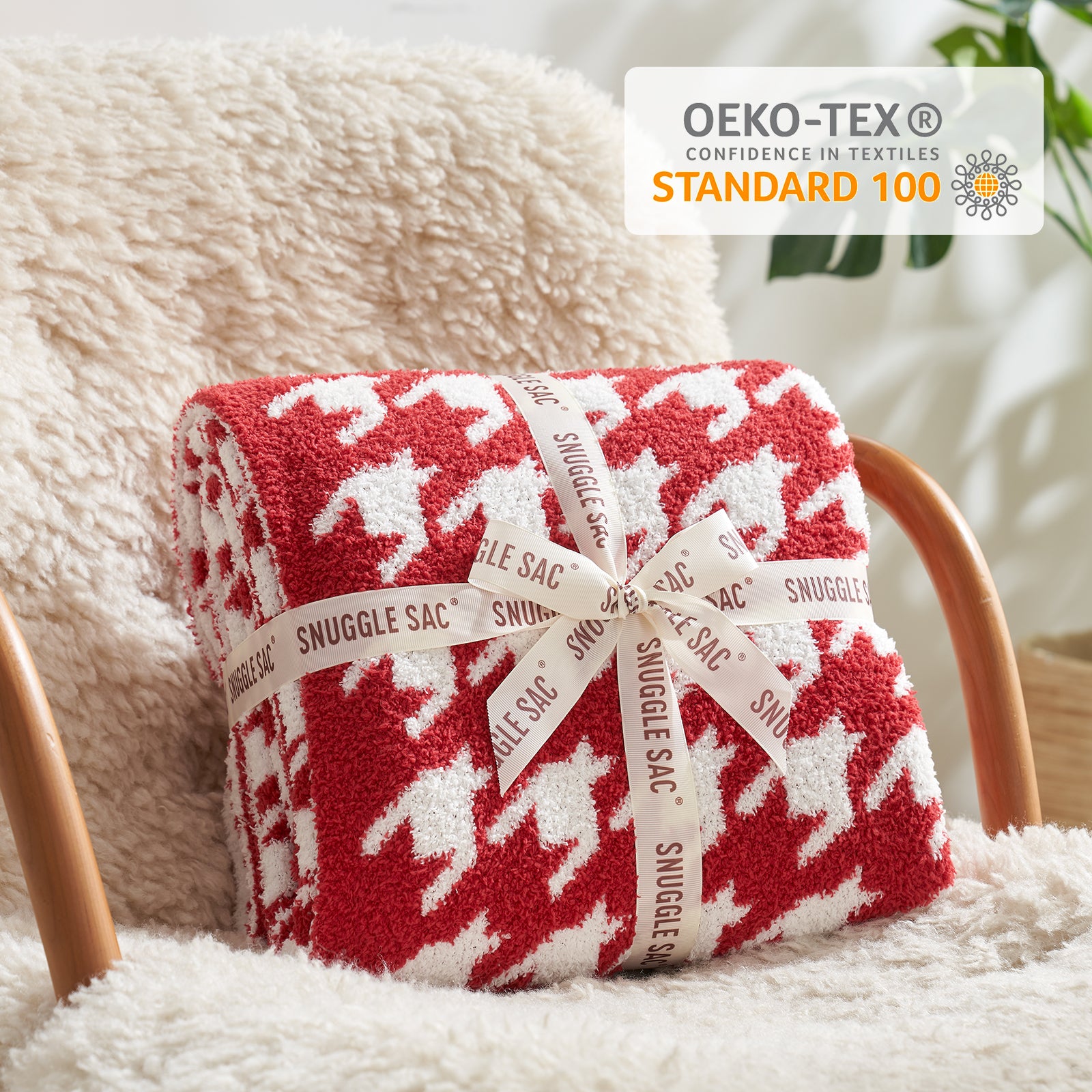 Red and white patterned blanket with 'Snuggle Sac' label on a soft surface, featuring OEKO-TEX certification.#color_Red