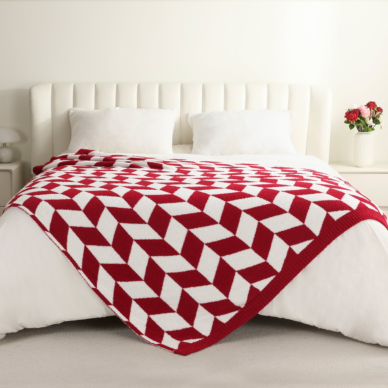 Red and white patterned blanket on a bed in a bedroom setting #color_Red