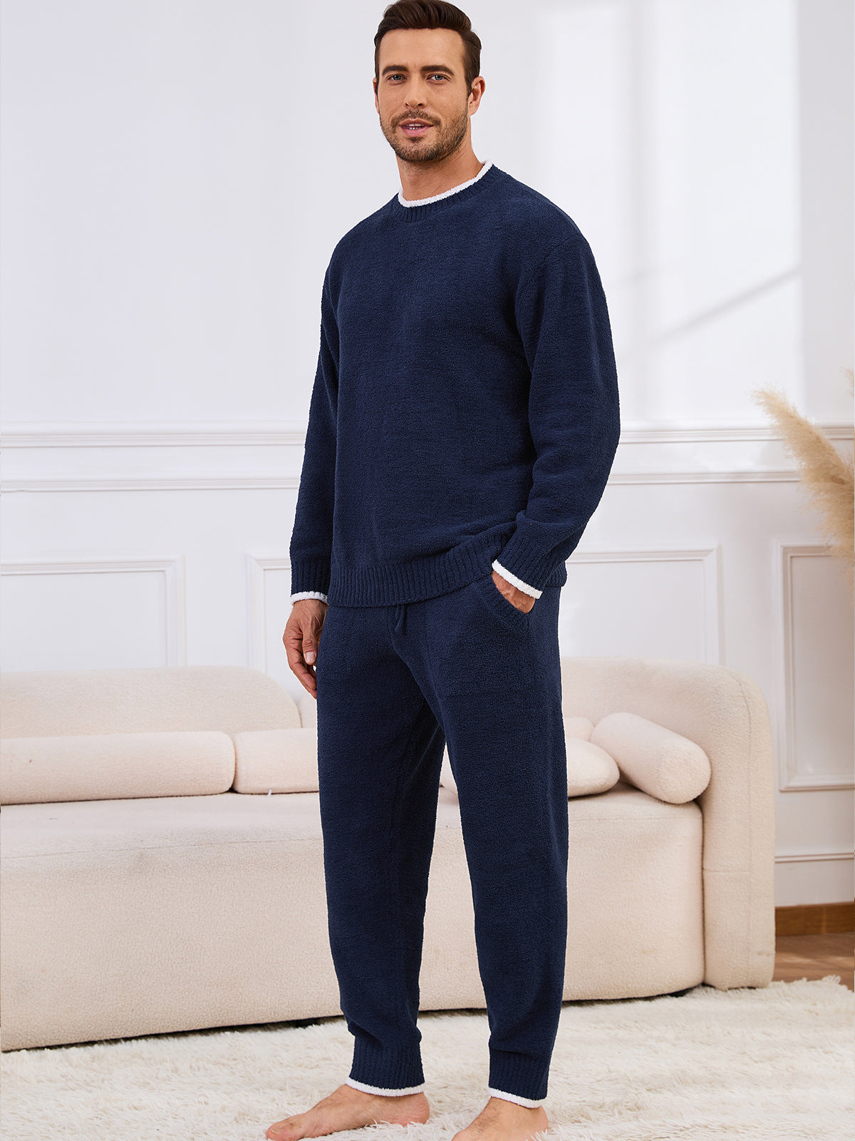 Man wearing a navy blue sweater and pants in a living room setting. #color_Navy