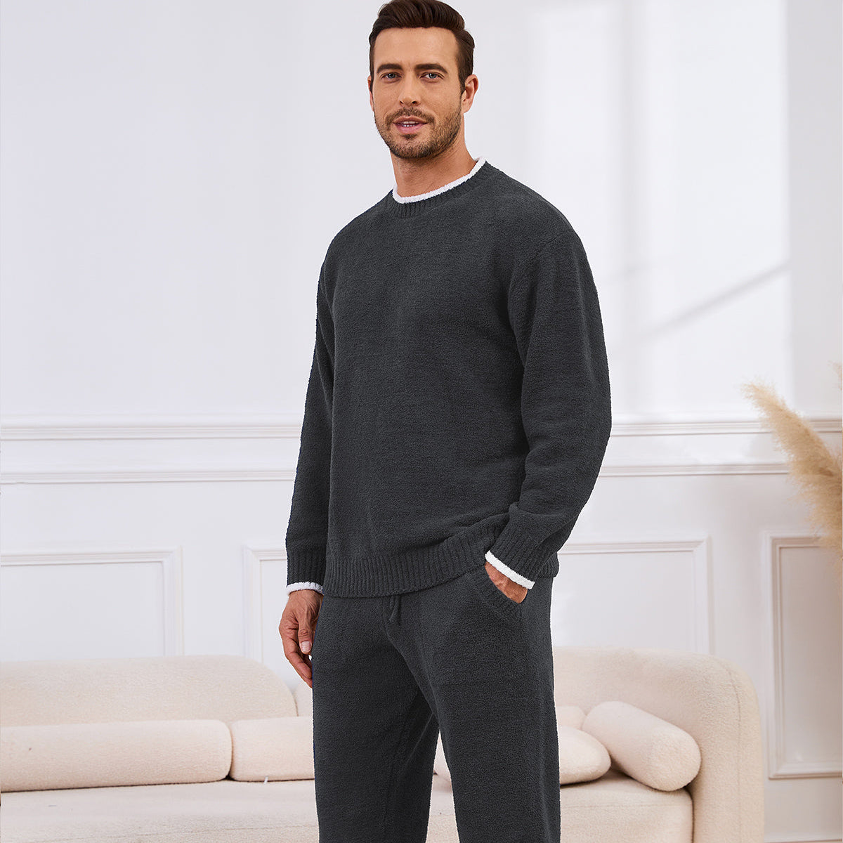 Man wearing a dark gray sweater and pants in a living room setting. #color_Dark Grey