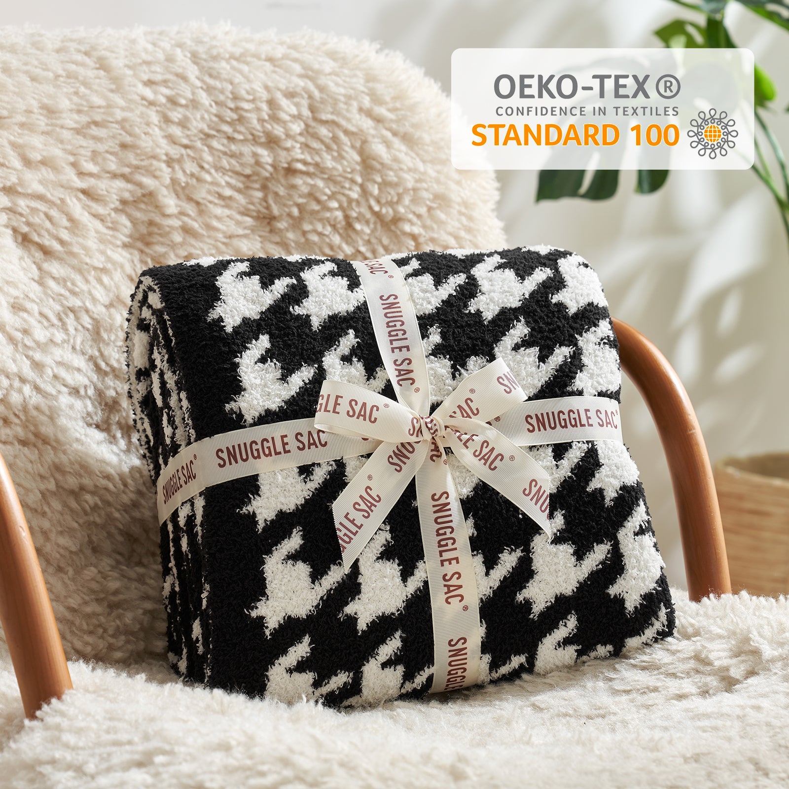 Black and white patterned blanket with 'Snuggle Sac' label on a fluffy surface, featuring OEKO-TEX Standard 100 logo. #color_Black