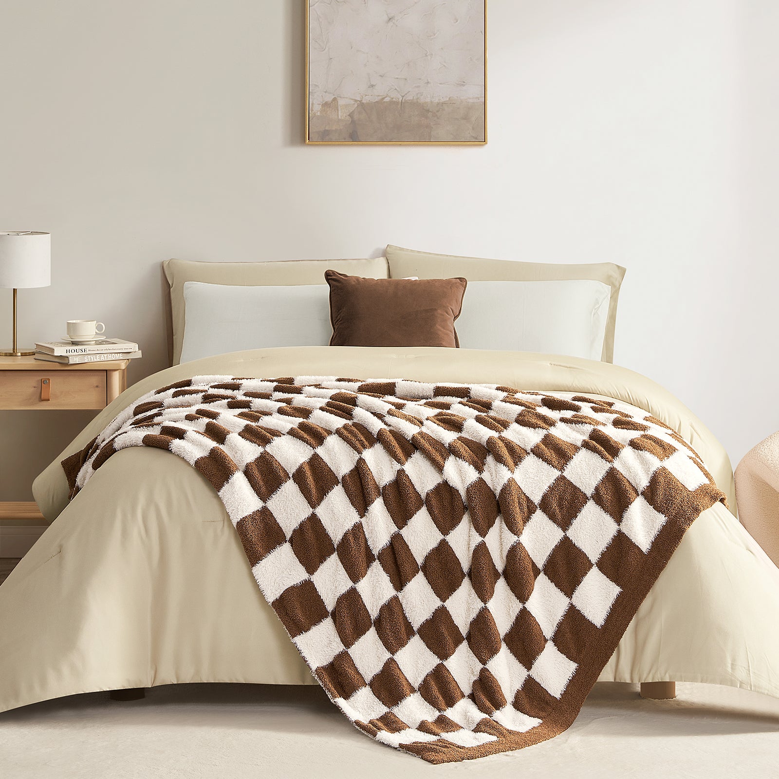 Bed with a brown and white checkered blanket, beige bedding, and a nightstand with a lamp.#color_Brown