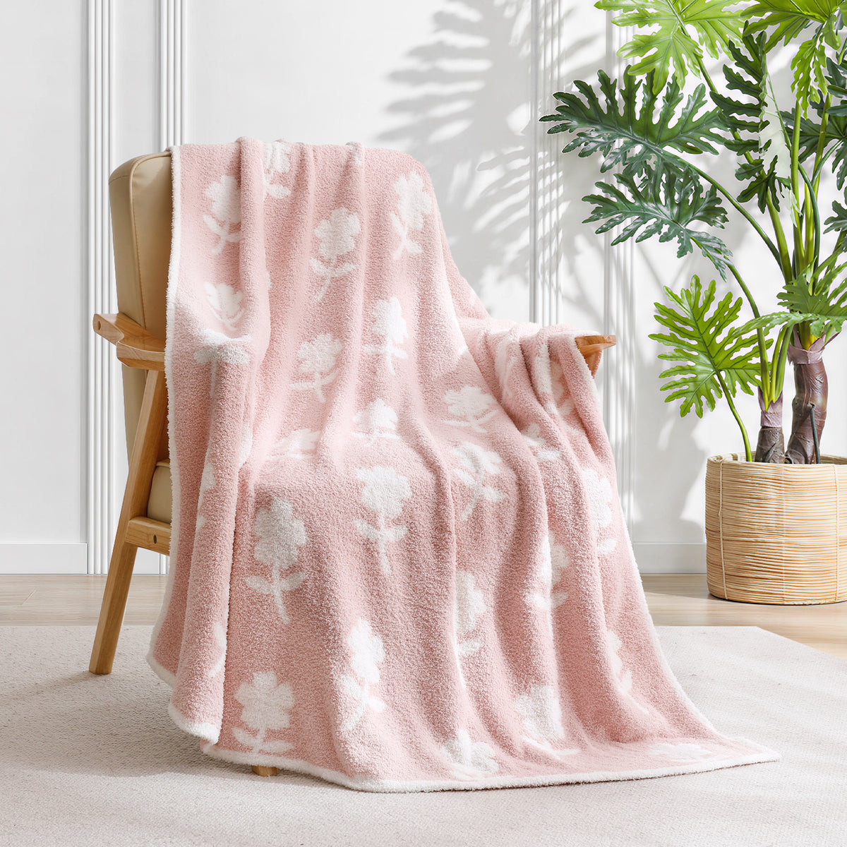 Flower blanket draped over a chair in a cozy room with plant in the background. #color_Pink