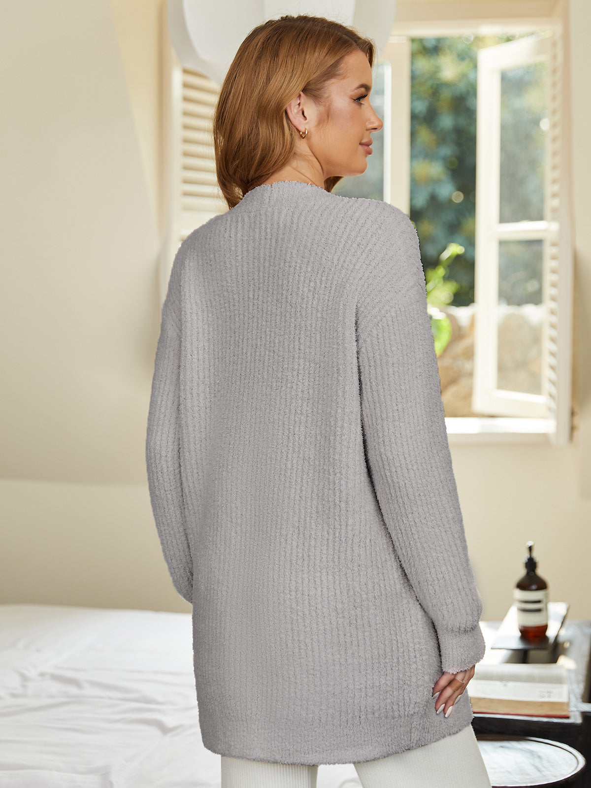 Woman wearing a gray cardigan in a room with a window and decor. #color_Grey