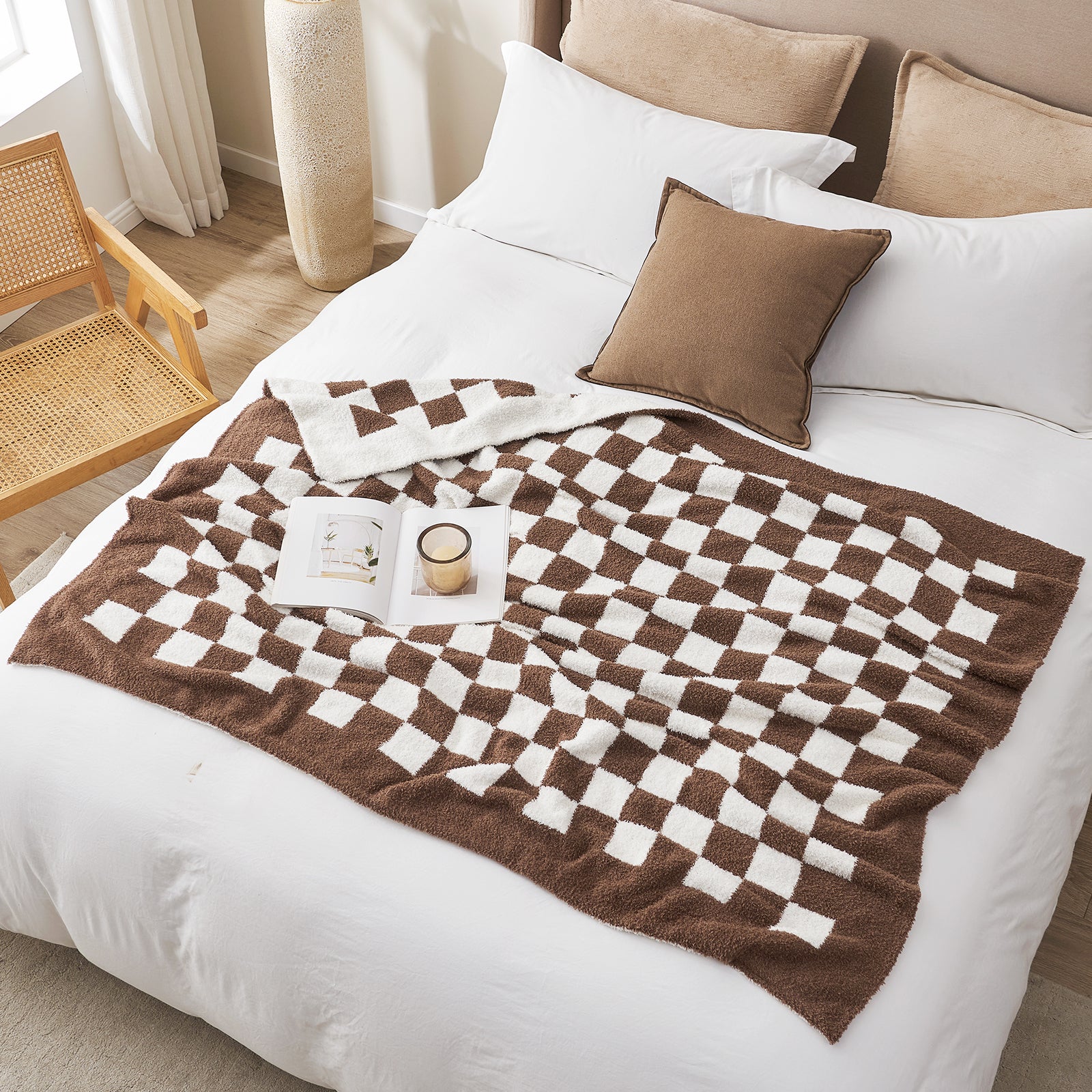 Bed with a brown and white checkered blanket, pillows, and a book on a wooden floor. #color_Checkered Brown
