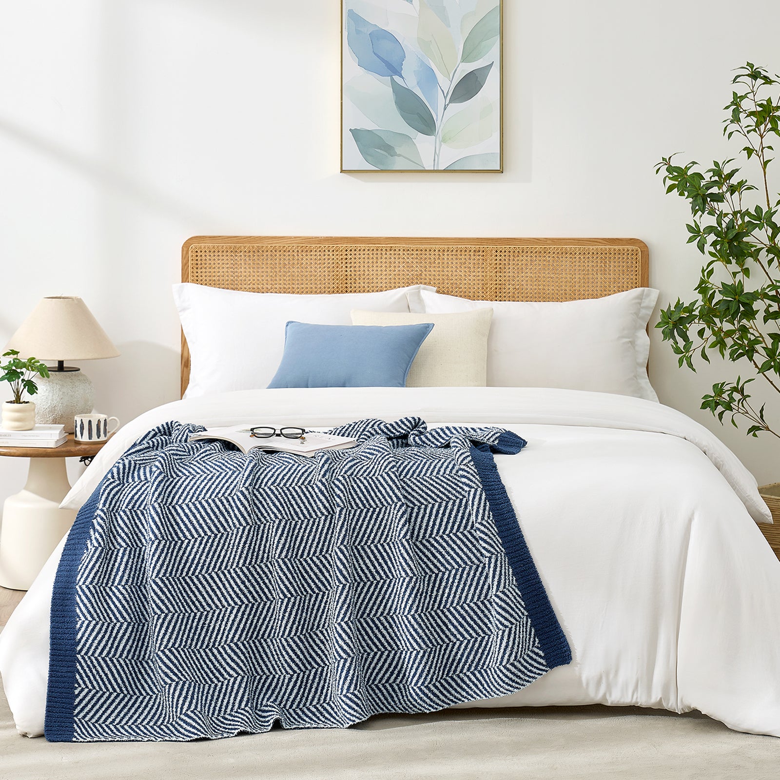 Snuggle Sacs Herringbone Feather Yarn Knit Throw Blanket on the bed with glasses and magazine on the blankt and plant and lamp as decorations#color_Navy