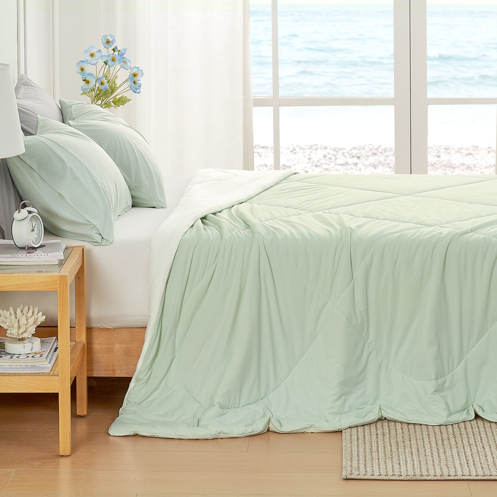 Left side view of green comforter on a bed in a bright bedroom with large windows.#color_Mint Green