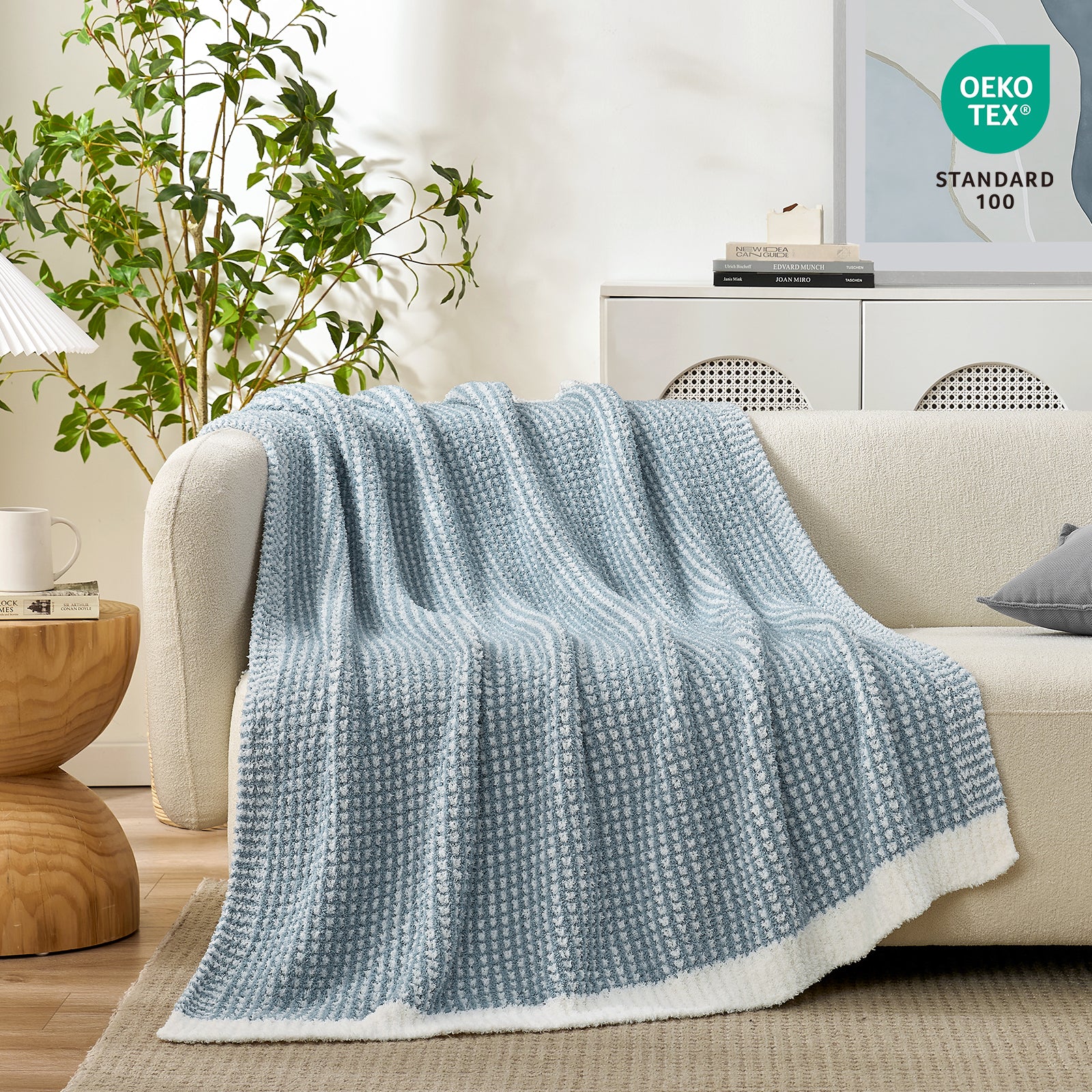 Soft Waffle Feather Yarn Knit Throw Blanket draped on a white sofa with plant and mug#color_Cream/Blue
