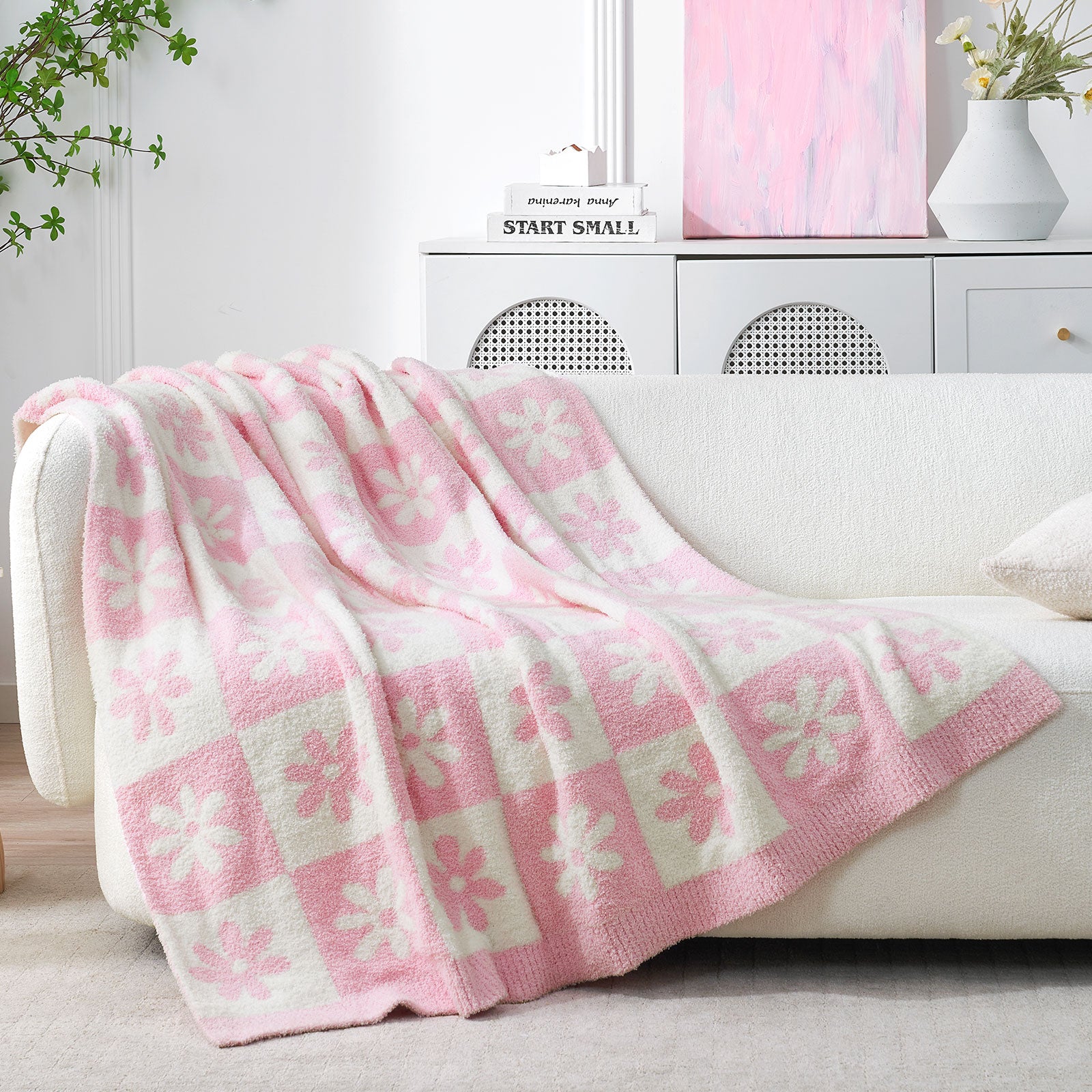 Pink and white checkered blanket draped over a white sofa in a living room setting. #color_Baby Pink
