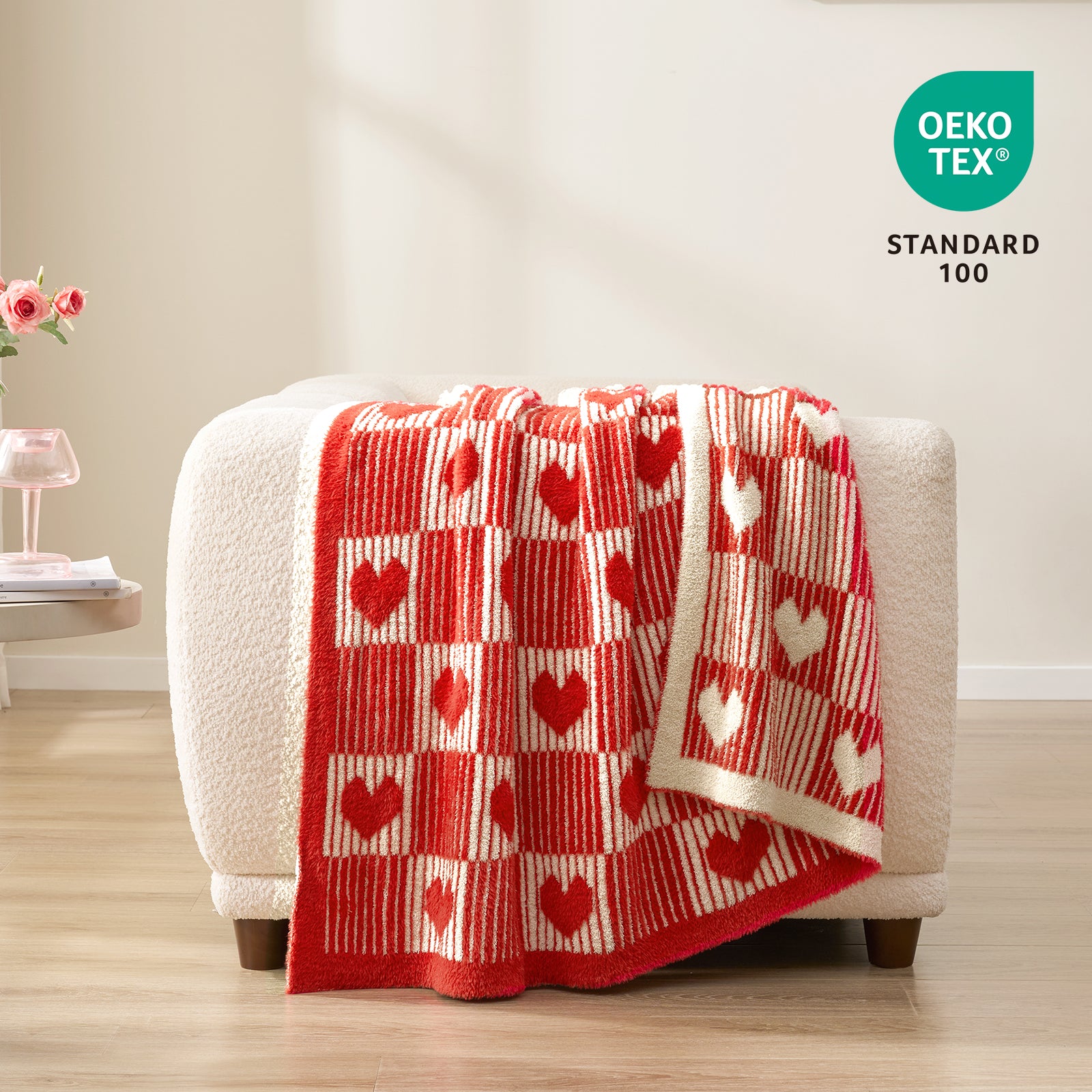 Red and white checkered blanket with heart patterns draped over a white chair, featuring OEKO-TEX Standard 100 logo. #color_Red Heart