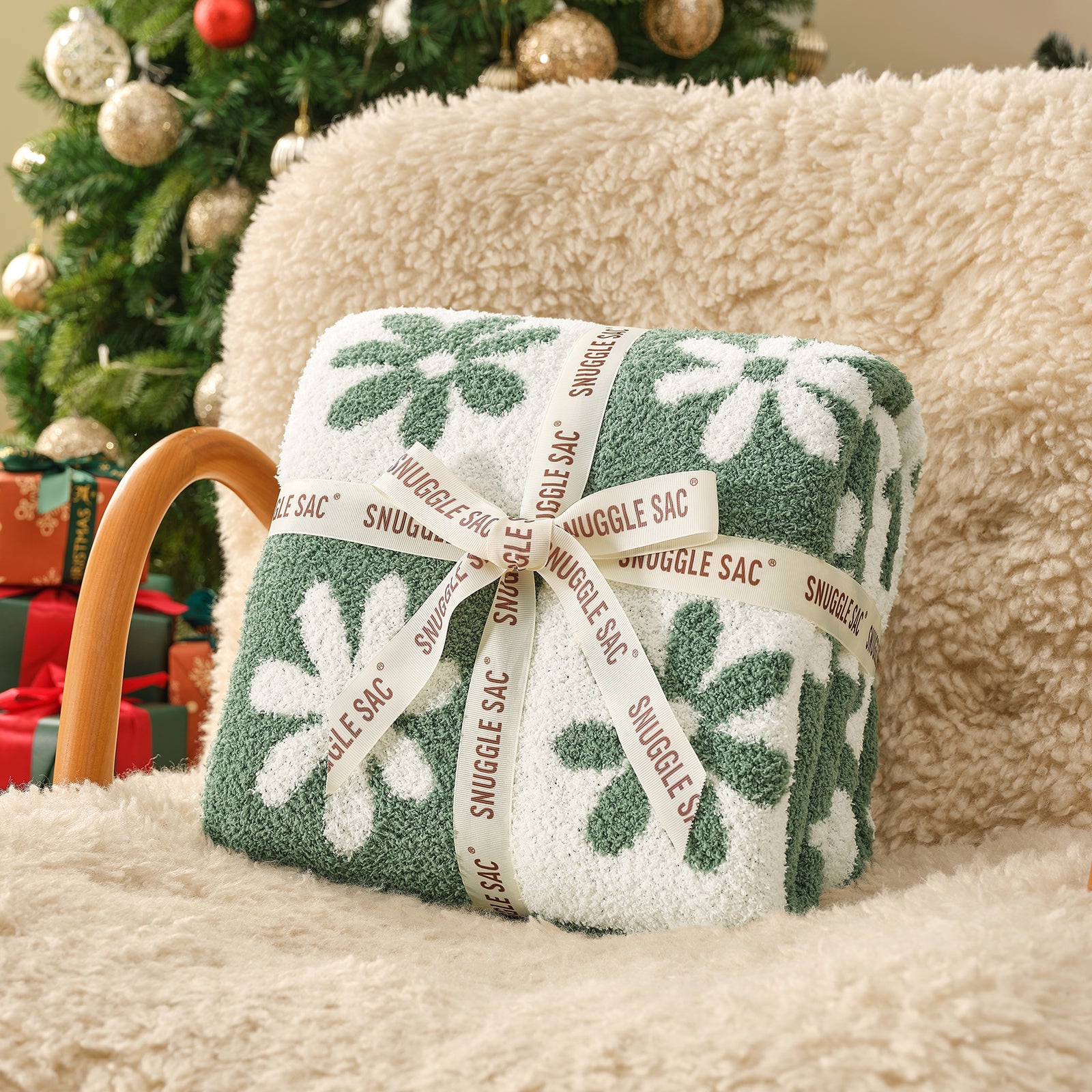 Green and white patterned Snuggle Sac on a beige surface with a Christmas tree in the background #color_Xmas Green