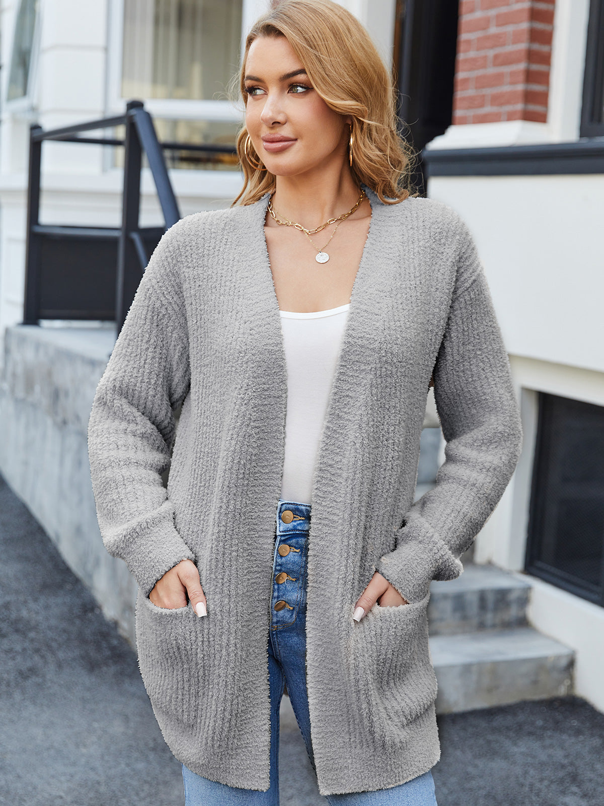 Woman wearing a gray cardigan standing outdoors. #color_Grey