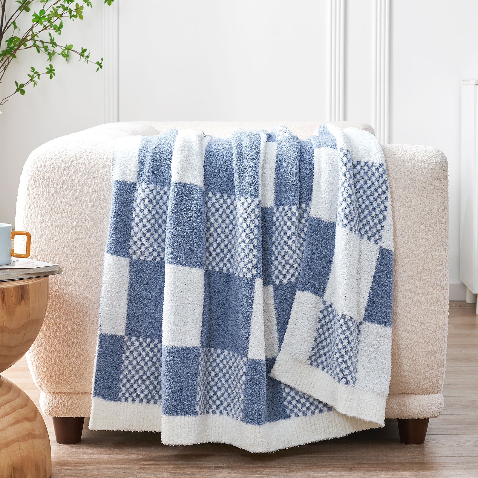 Blue and white checkered blanket draped over a beige armchair in a home setting. #color_Pale Blue