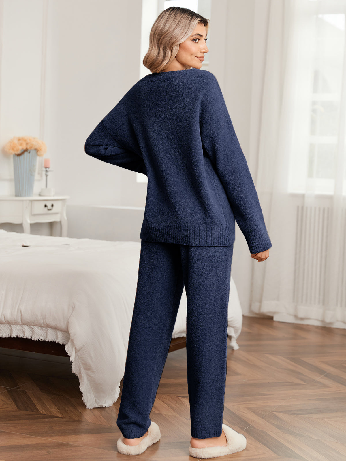 Woman wearing a navy blue outfit standing in a bedroom. #color_Navy