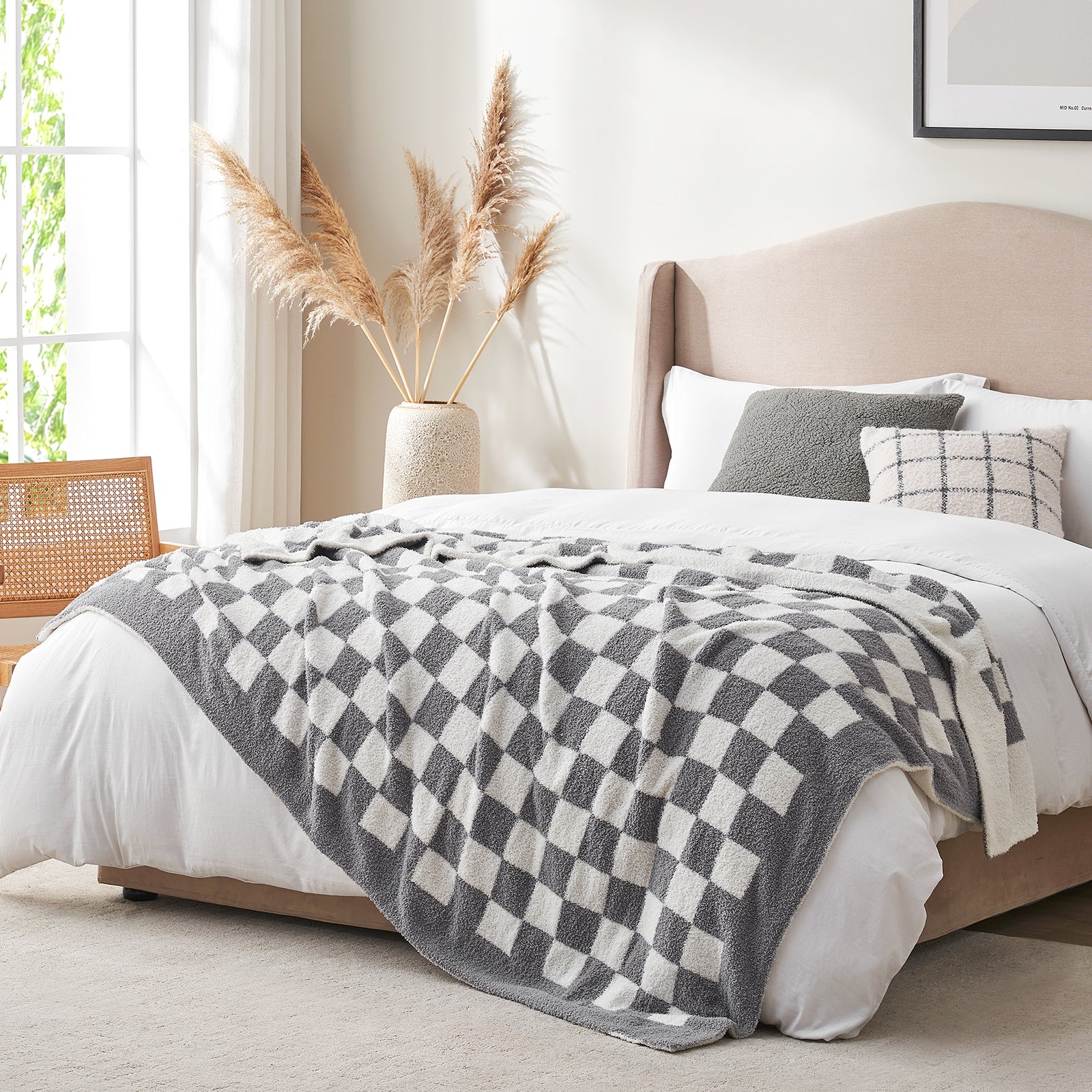 Bedroom with a bed featuring a checkered blanket, pillows, and a vase with pampas grass. #color_Checkered Grey