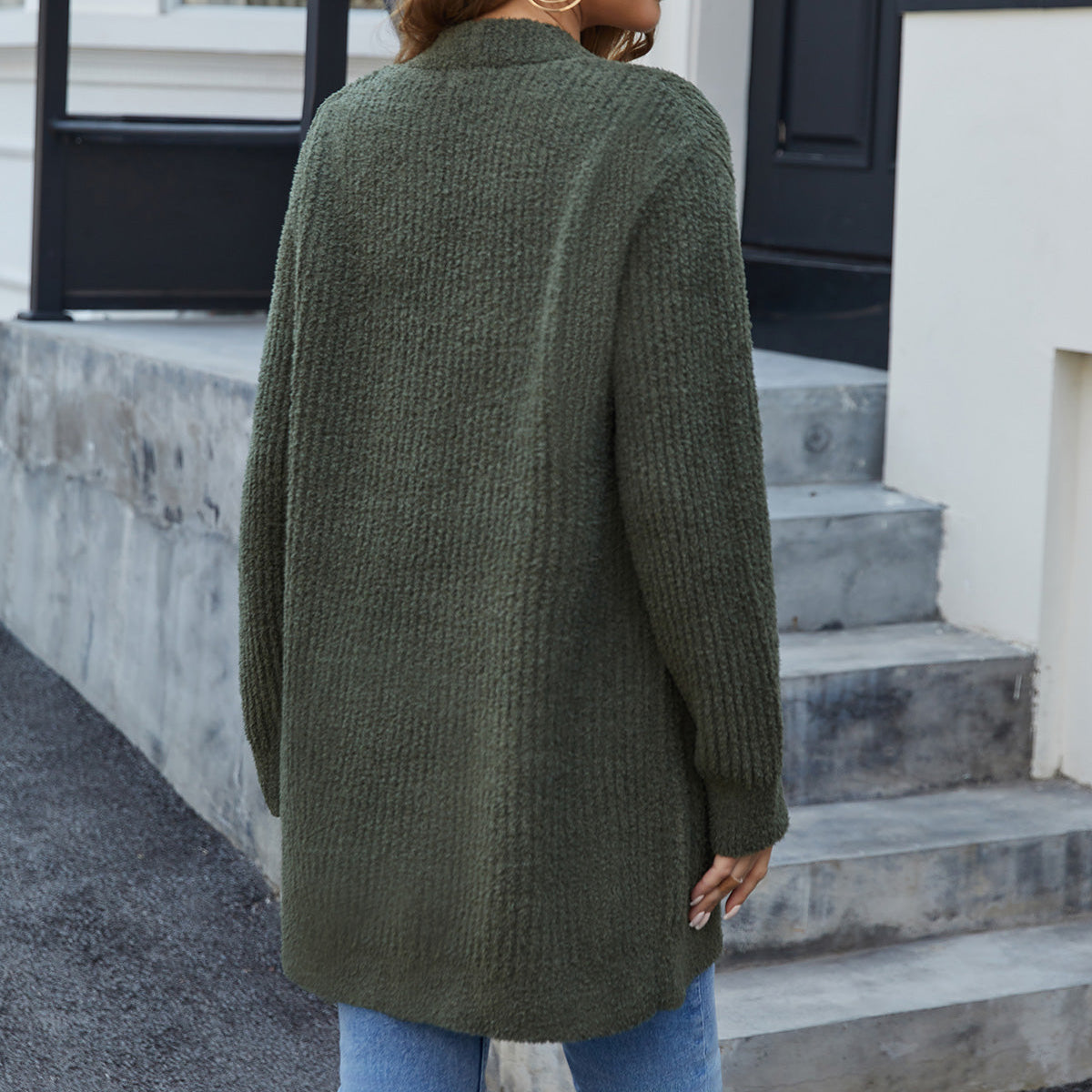 Woman wearing a green cardigan standing on steps outside a building. #color_Army Green