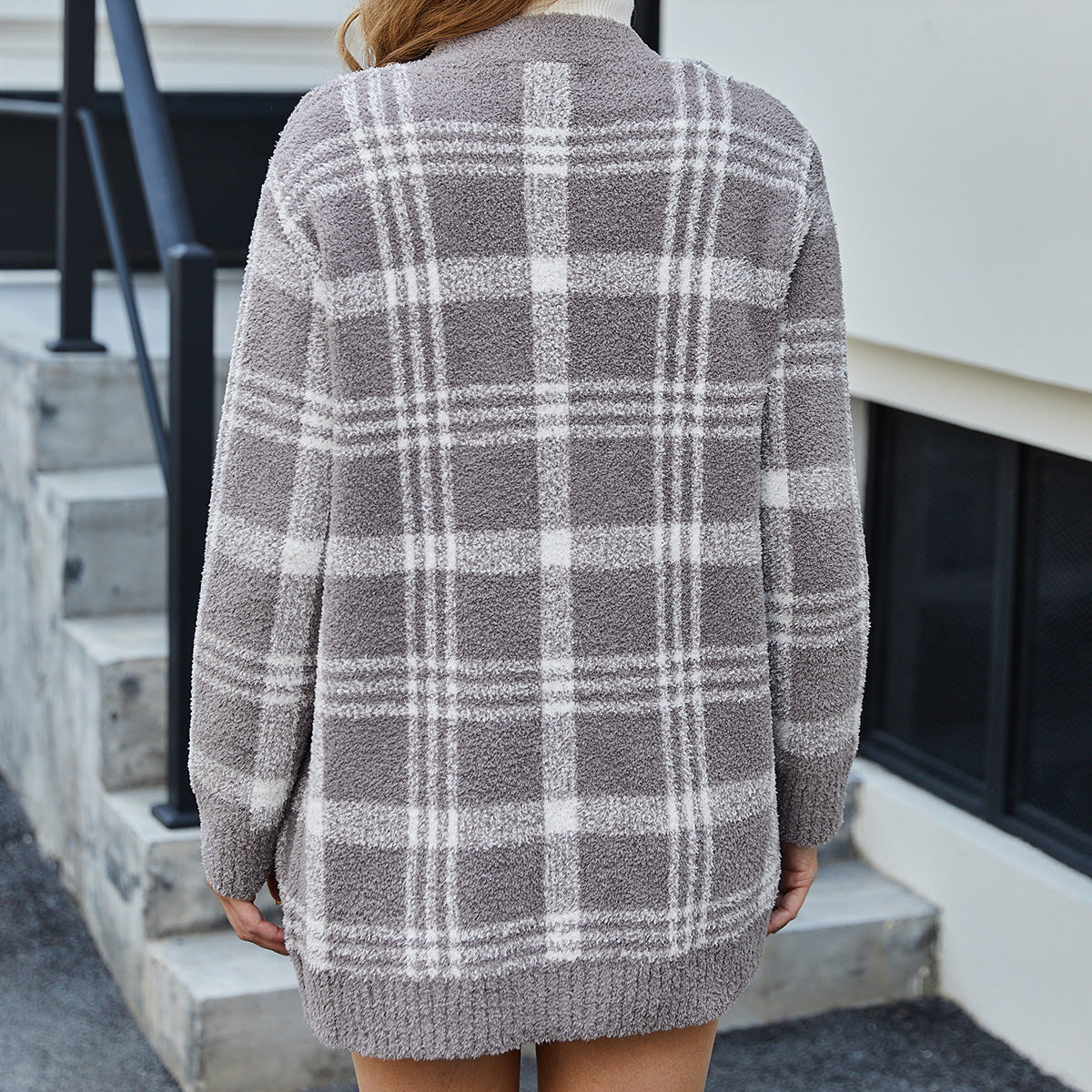 Person wearing a gray and white plaid cardigan standing on a porch. #color_Taupe Check
