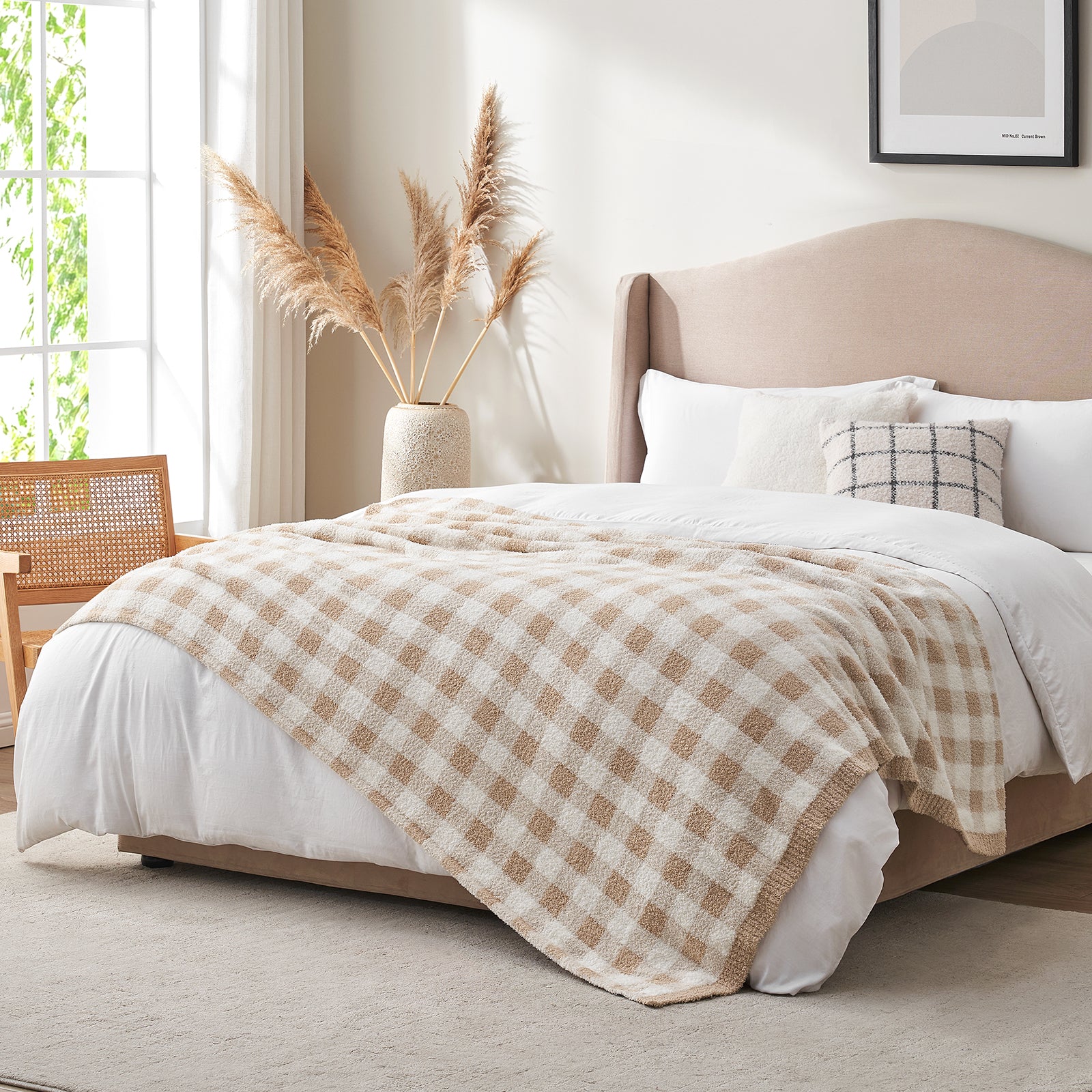 Bedroom with a bed covered by a beige checkered blanket, pillows, and a vase with pampas grass. #color_Plaid Beige