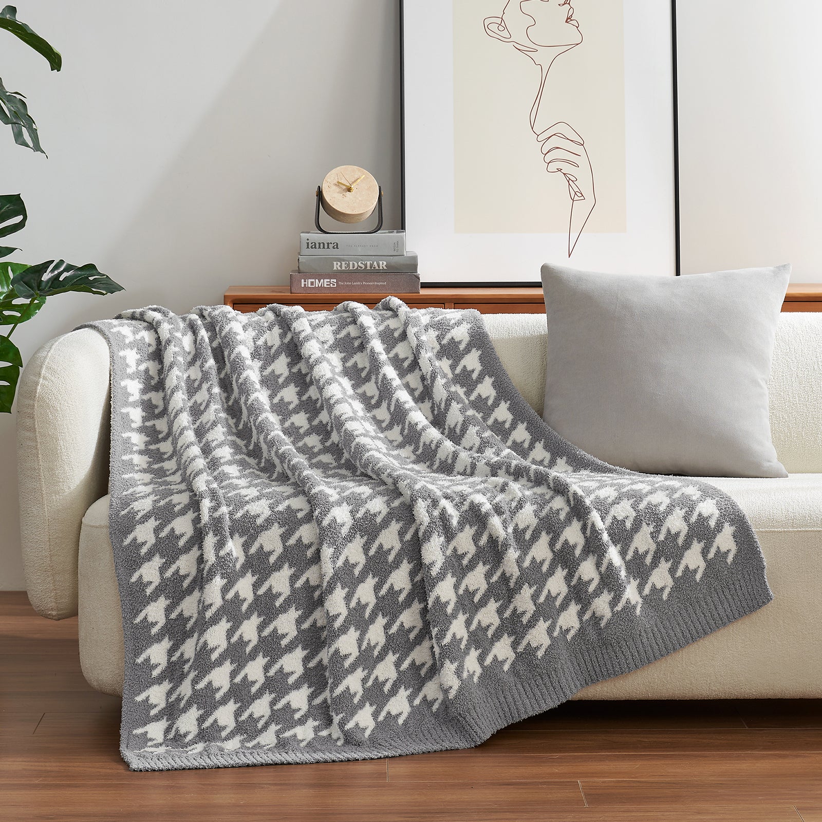 Gray and white houndstooth patterned blanket draped over a beige sofa in a living room. #color_Grey