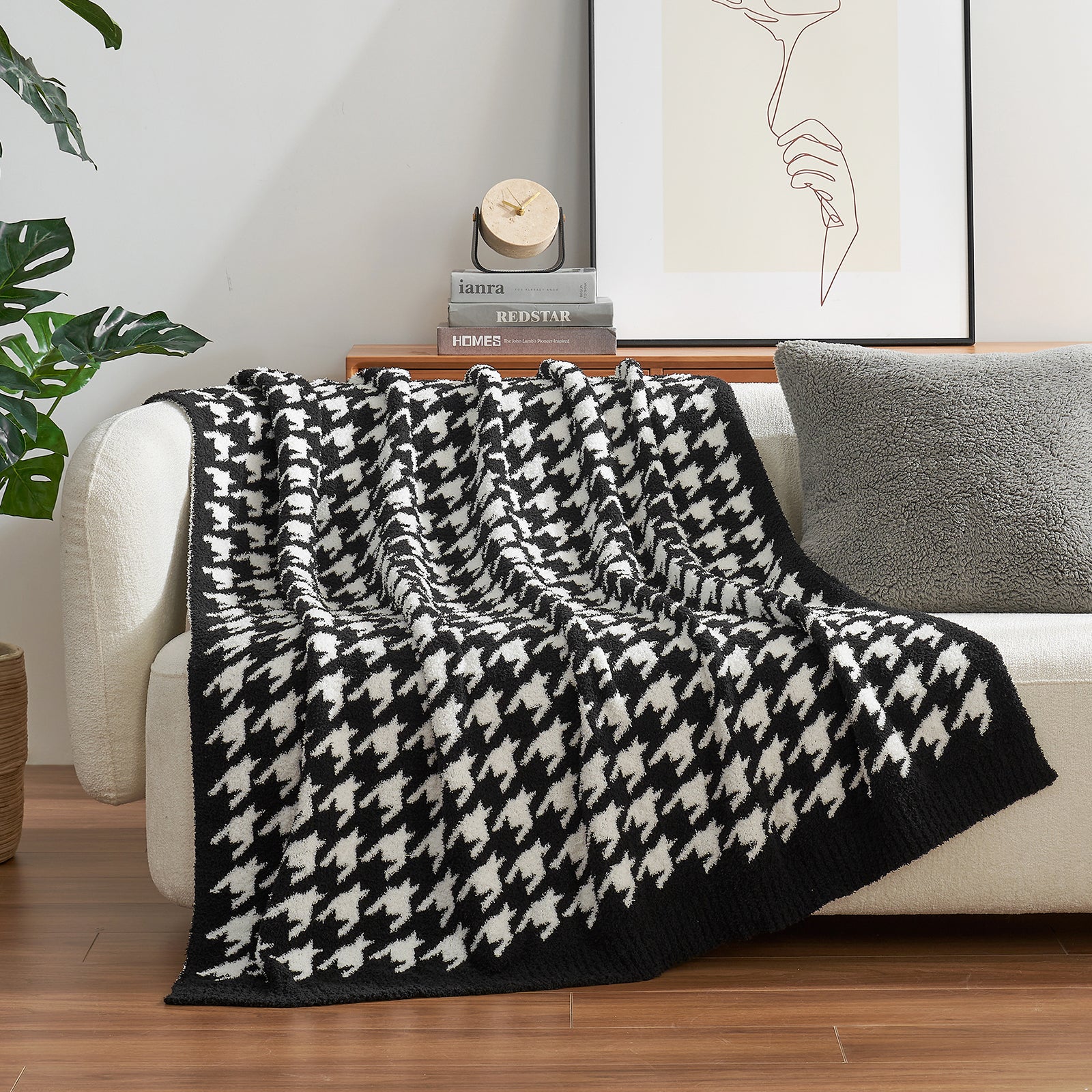 Black and white houndstooth patterned blanket draped over a sofa in a living room setting. #color_Black