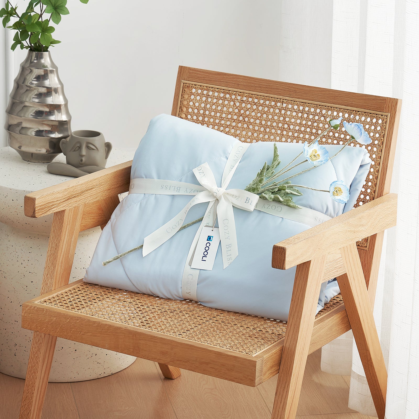 Cooling comforter with a white ribbon on a wooden chair, perfect as gift.#color_Grey/Blue