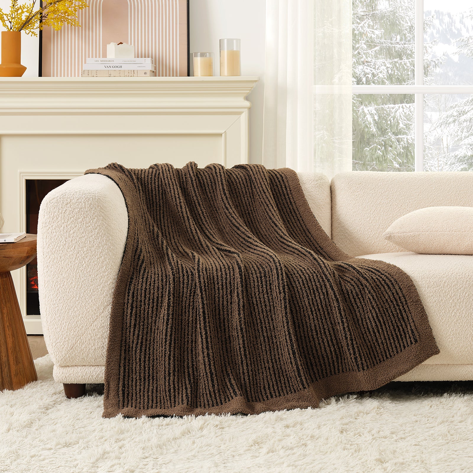 Brown blanket draped over a beige sofa in a cozy living room with a fireplace. #color_Brown/Black