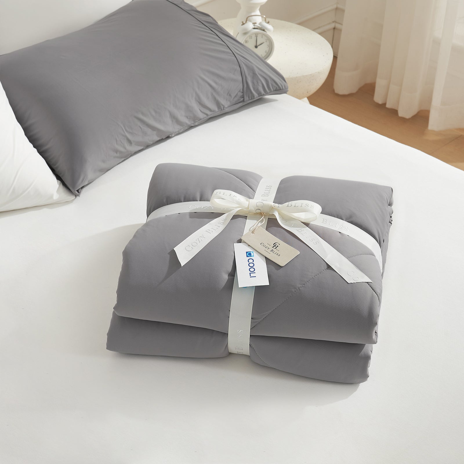 Cooling comforter with a white ribbon on bed, perfect as gift.#color_Dark Grey