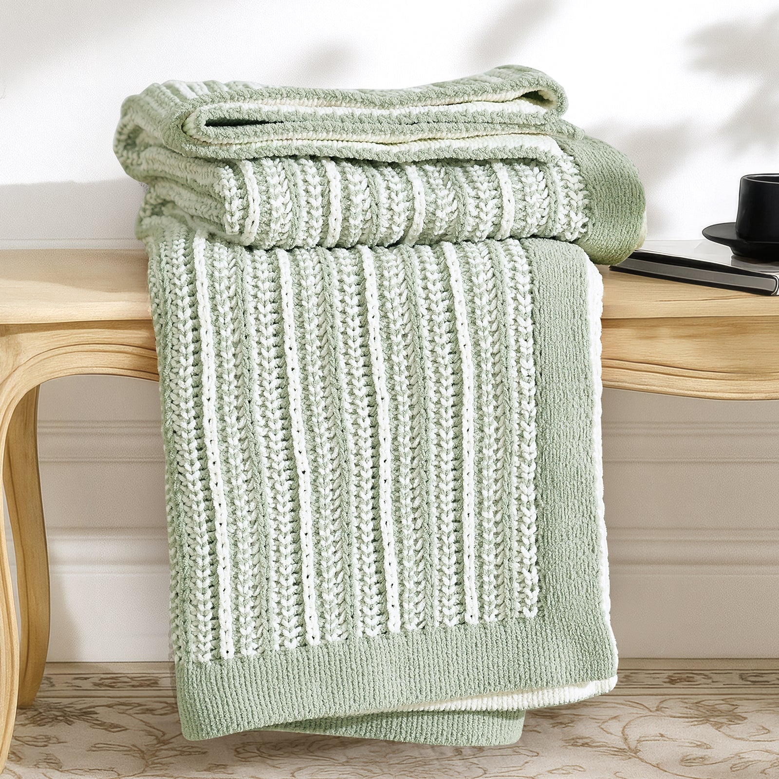 Snuggle Sac green knitted blanket on a wooden bench with a blurred background #color_Sage Green