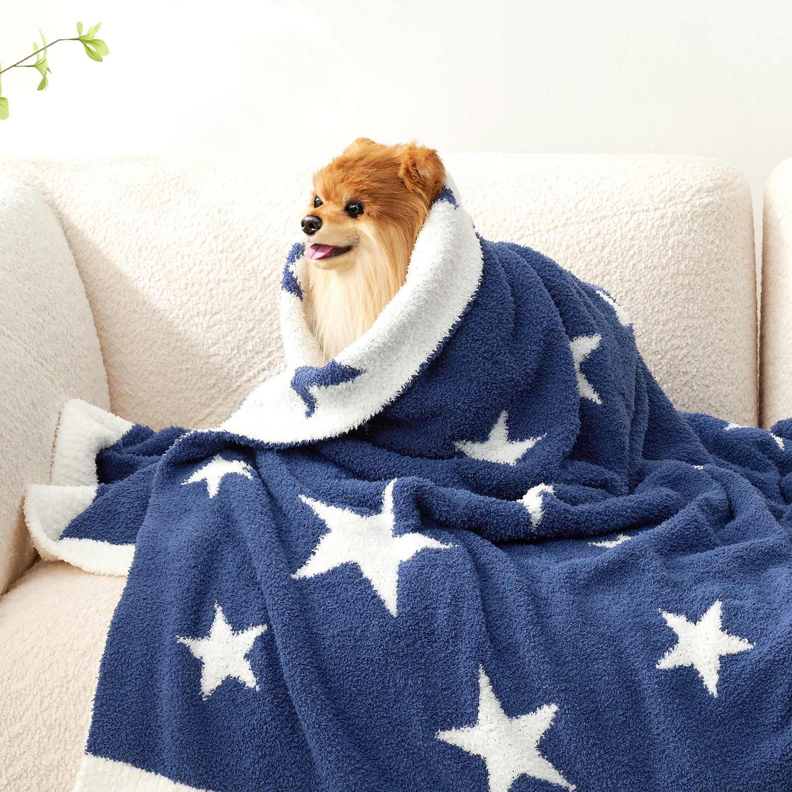 A dog wrapped under Snuggle Sacs Reversible Star Feather Yarn Knit Throw Blanket, standing on a beige couch#color_Royal_Heather_Blue
