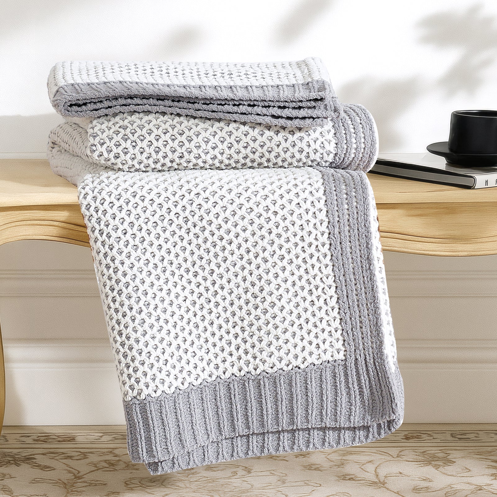 Stack of Snuggle Sac gray textured towels on a wooden surface with a blurred background #color_Gray&White